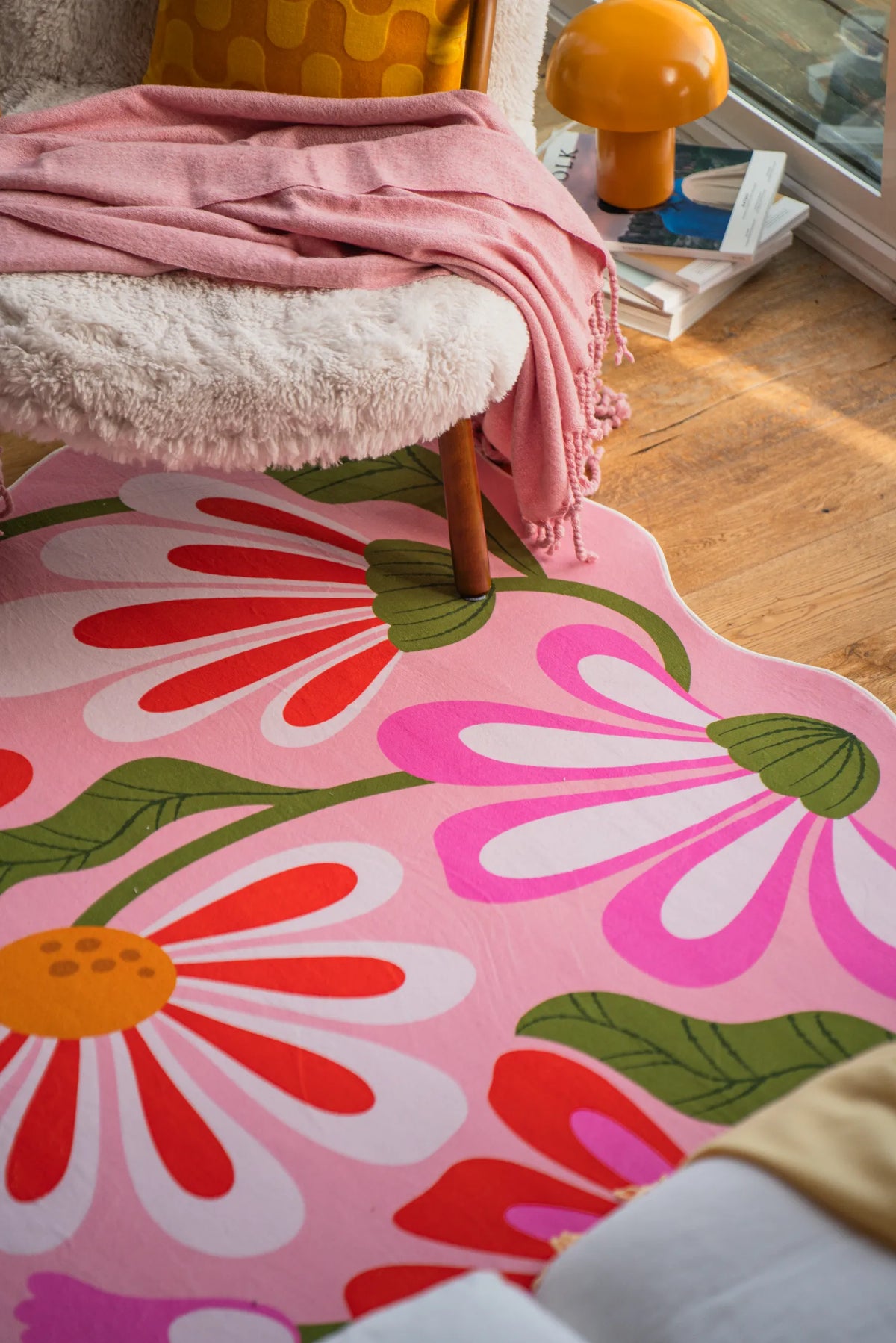 Close-up of pink floral wavy rug under a sherpa armchair in a cozy sunlit nook.