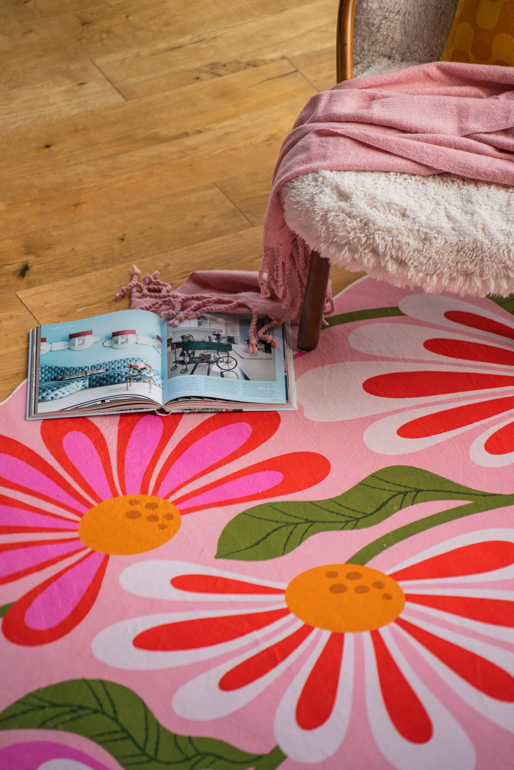 Close-up of pink floral wavy rug beneath a sherpa chair in a cozy reading corner.