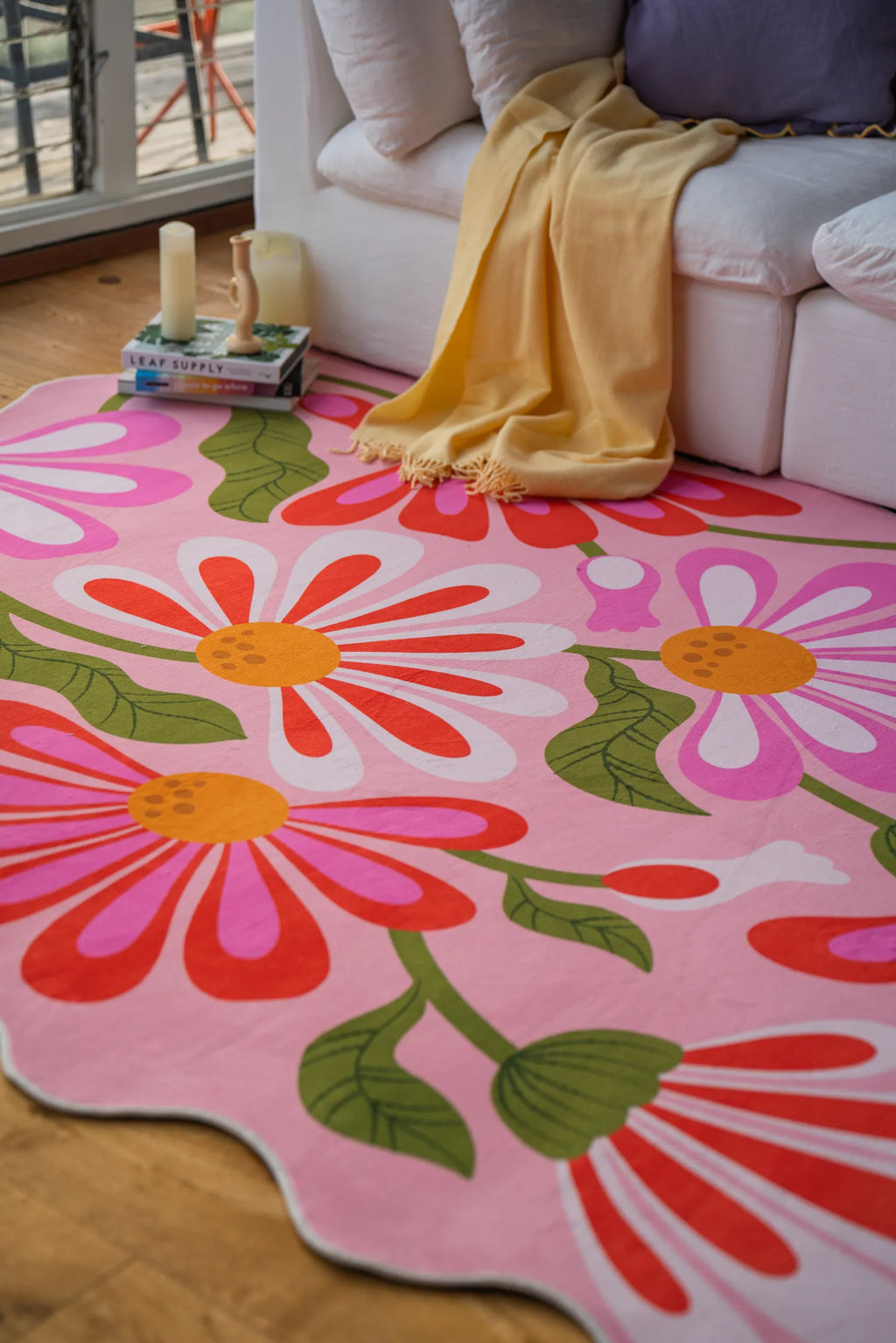 Pink floral wavy rug placed in front of a white sofa with wood flooring and soft natural light.