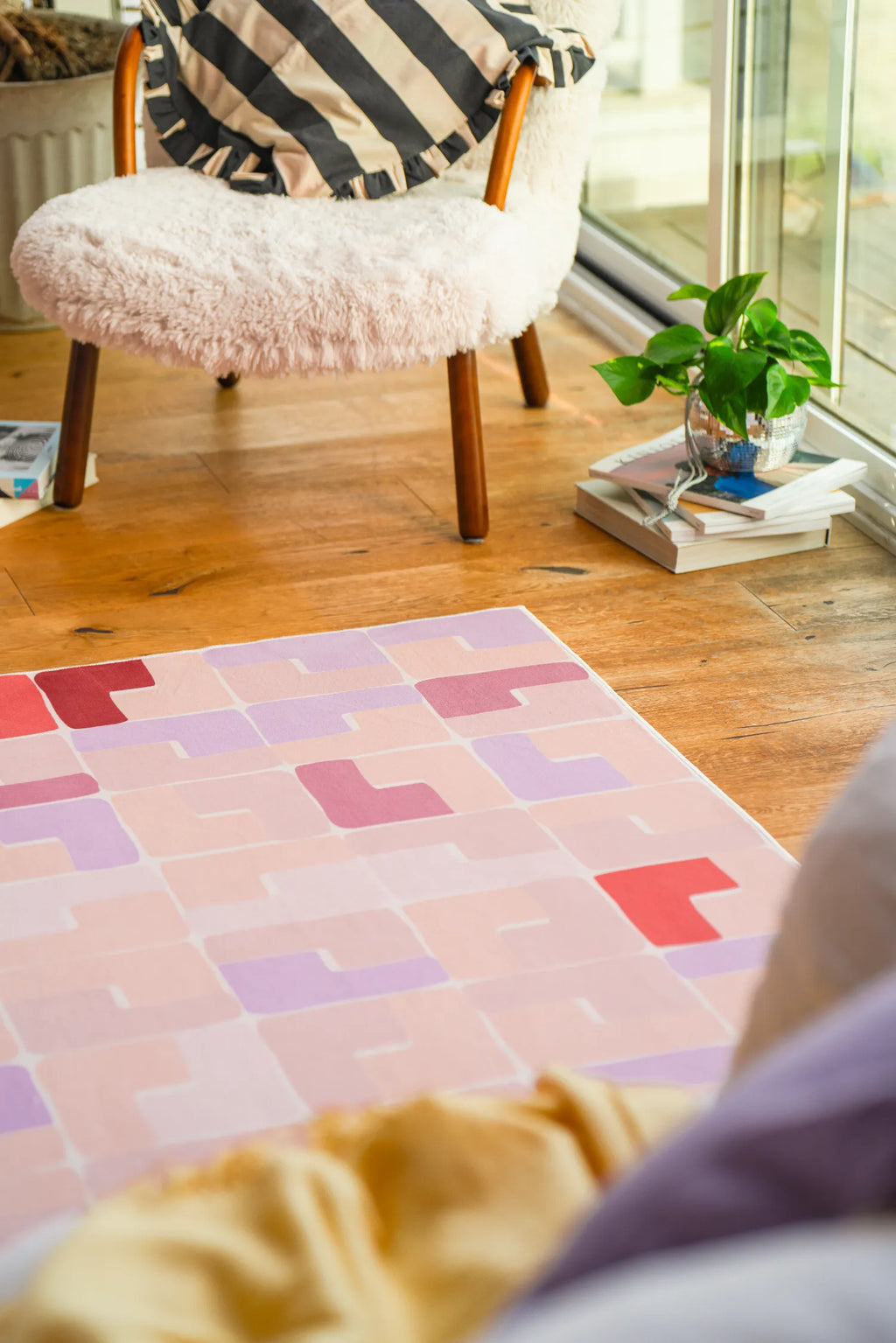 Modern pastel rug placed beside a sherpa chair in a sunlit reading nook.