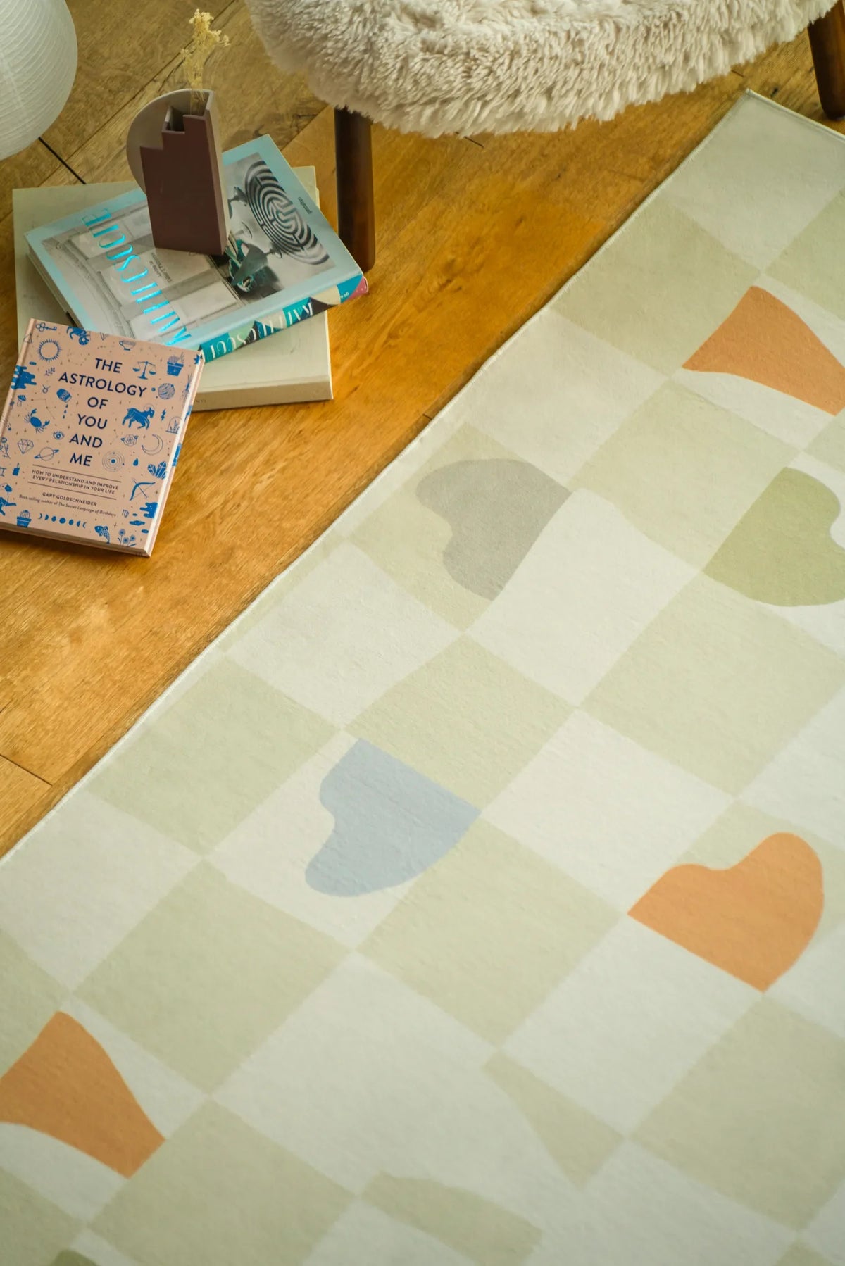 Close-up of the Modern Mosaic Neutral Pastel Rug by Jonnie Li laid on warm wood flooring in a relaxed corner.