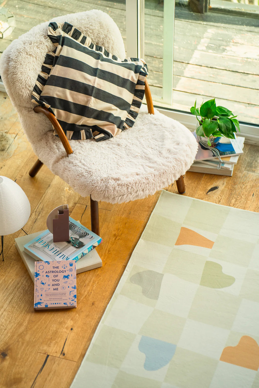 Pastel rug placed beside a boucle chair and large window, softening the light wood floor.