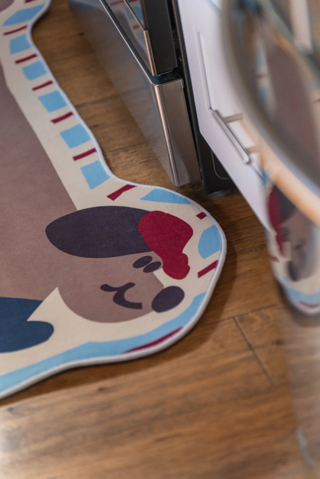 Close-up of the brown dog runner rug's head by the kitchen cabinets, showing its playful expression and curved shape.