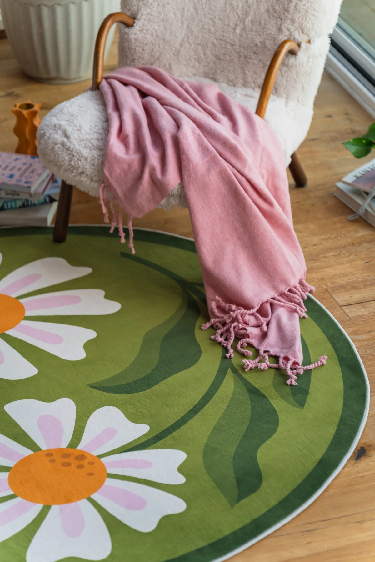 The Dual Daisy Round Rug in a cozy corner setup with a fluffy chair and a soft pink blanket.