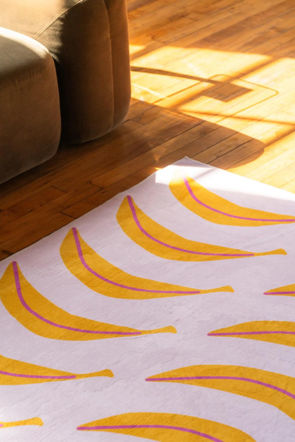 The funky banana runner stretches along the edge of a low sofa, catching sunlight across the wood floor