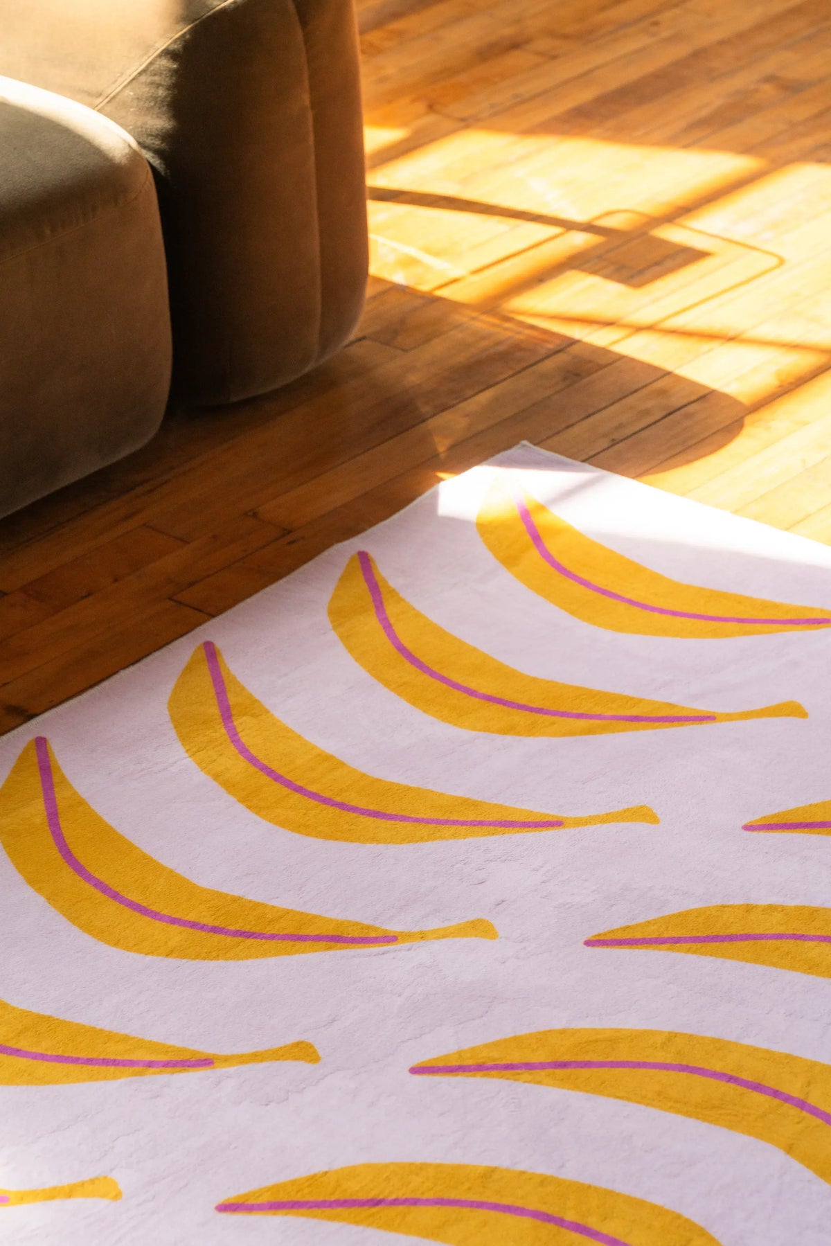 The funky banana runner stretches along the edge of a low sofa, catching sunlight across the wood floor