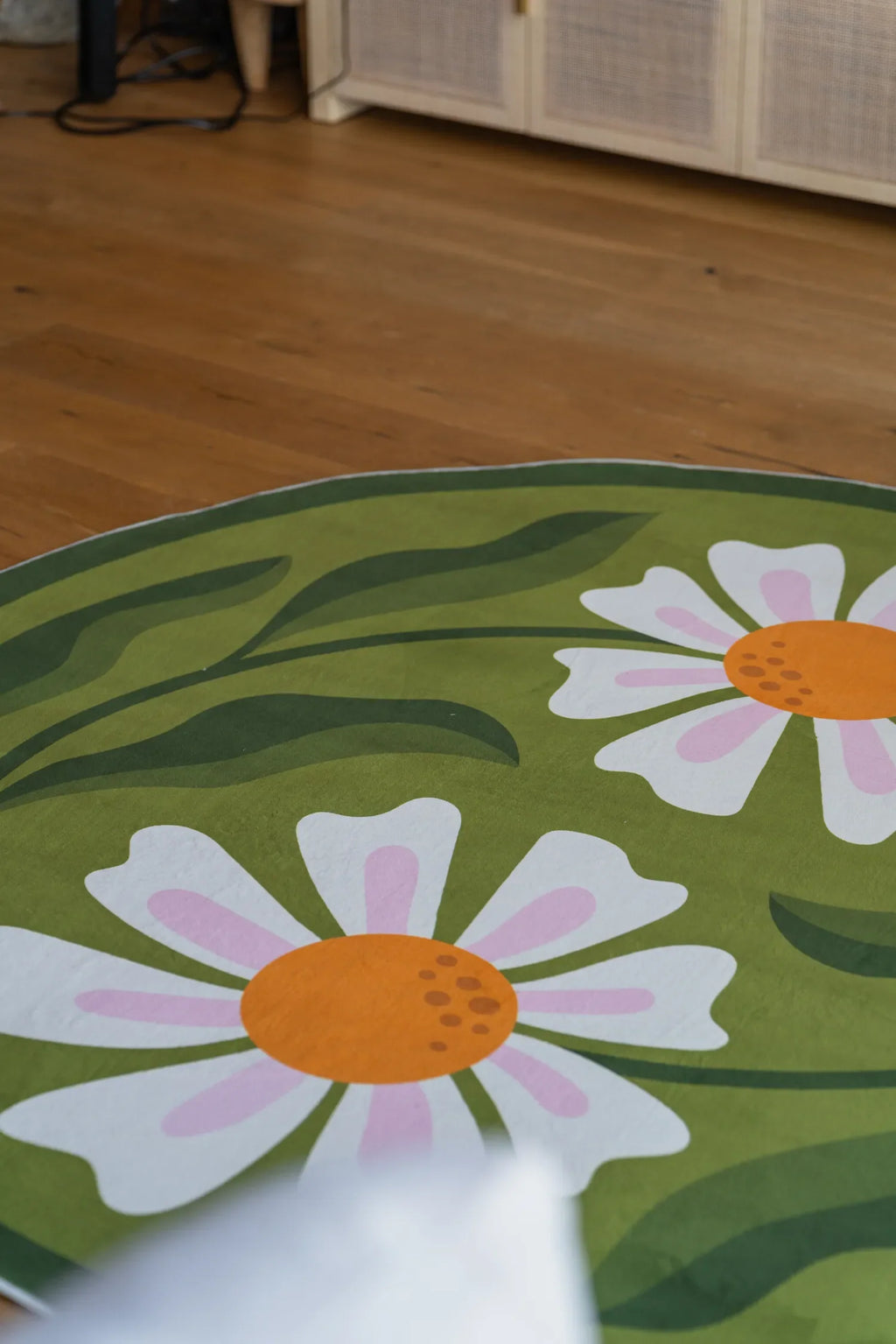 A detailed view of the daisy floral pattern on the Dual Daisy Round Rug, styled on wooden floor.