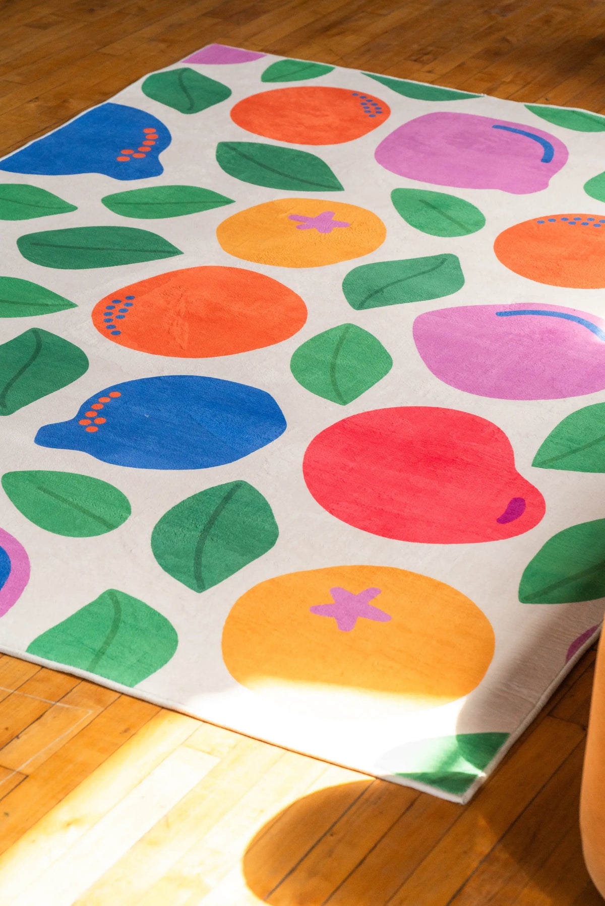 Bright pastel rug by Becca Franks laid on wood floor, catching light in a minimal, open space