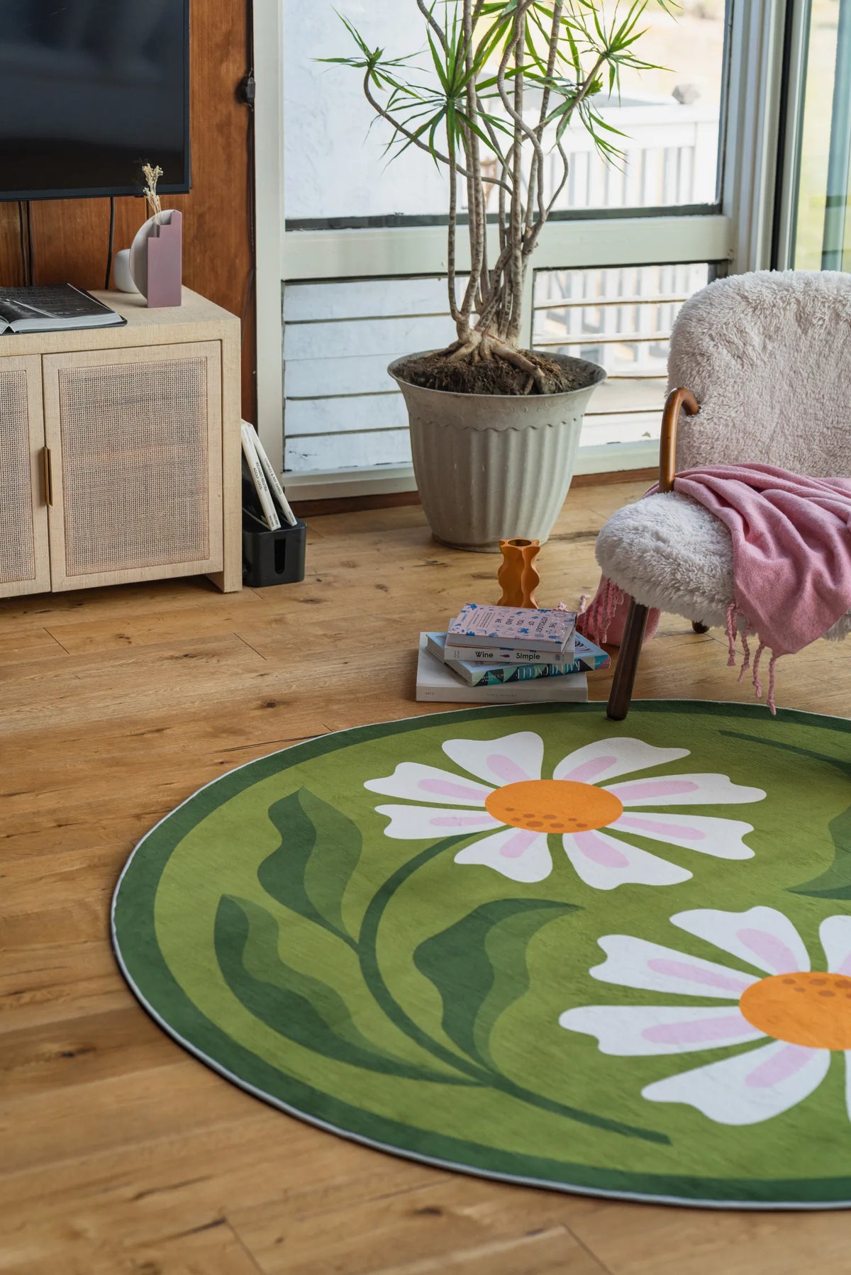 Dual Daisy Round Rug placed in a sunlit living room corner with a cozy chair and books.