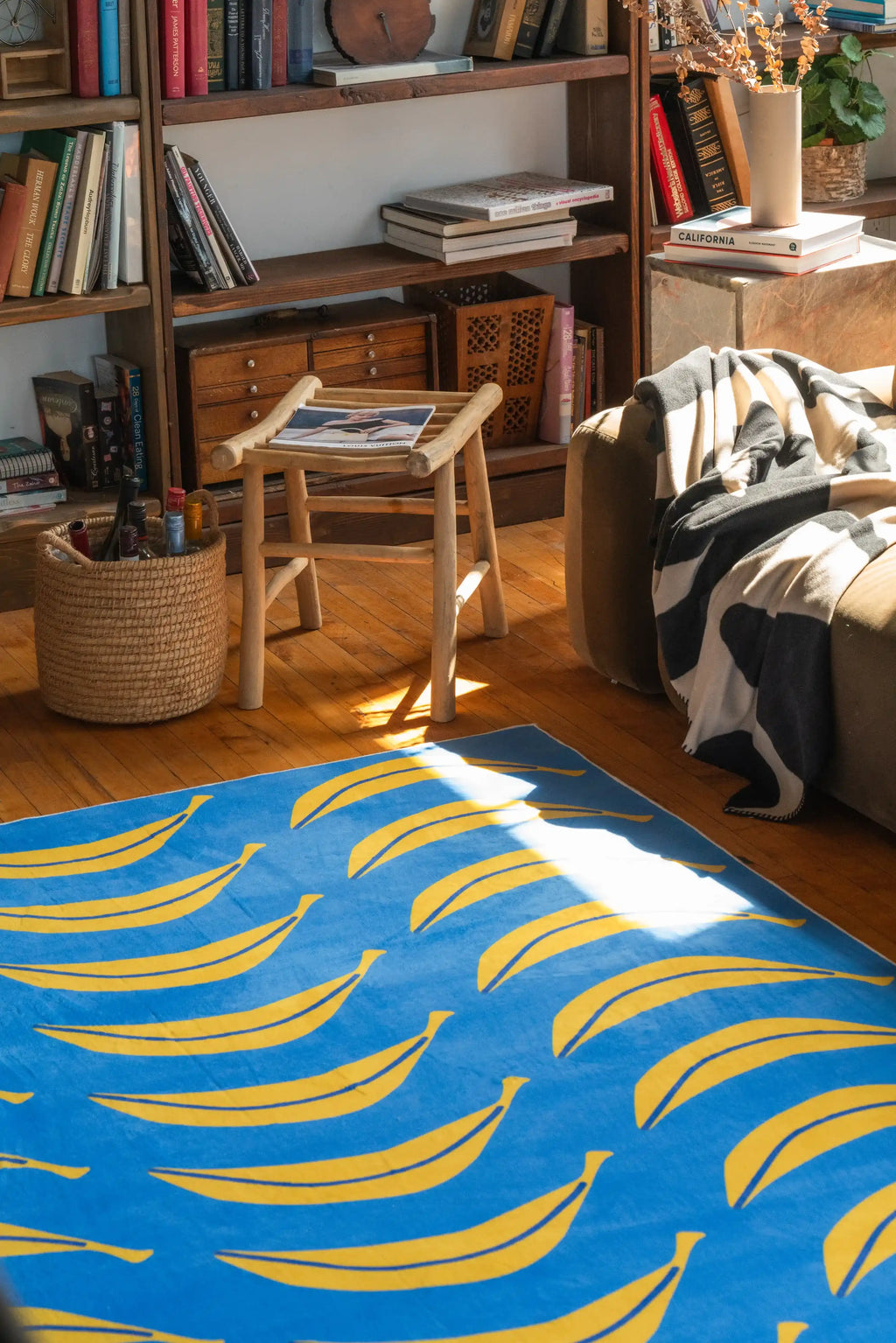 A corner of the Blue Banana Parade Funky Runner by Becca Franks, paired with a woven basket and book-filled shelve