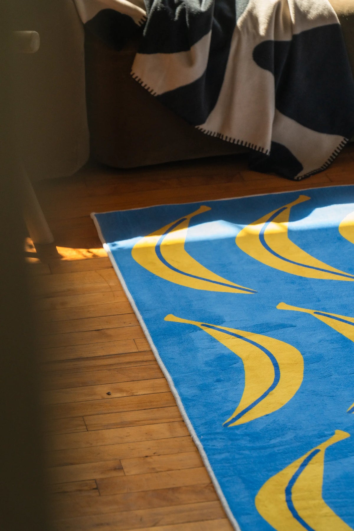 Detail of the Blue Banana Parade Funky Runner with bright yellow banana pattern, next to a cozy corner sofa