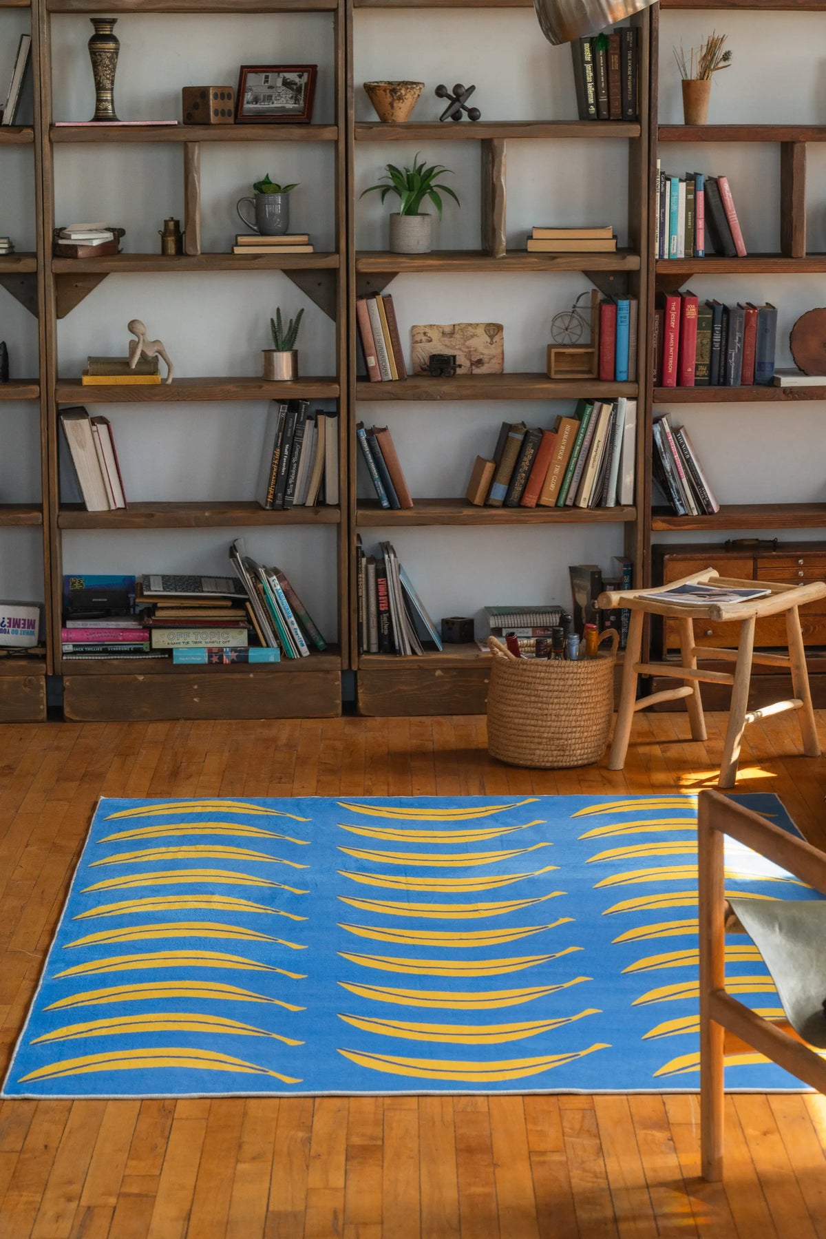 Banana runner rug in bold blue and yellow tones in front of bookshelf, on wood floor