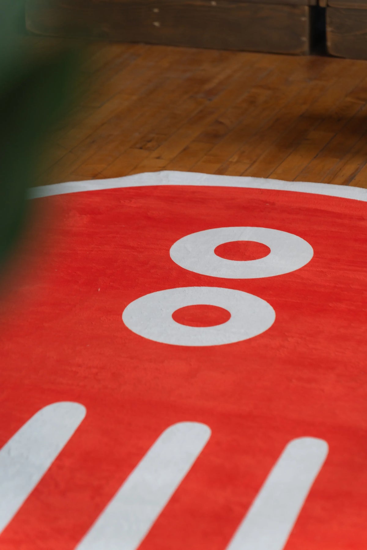 Close-up of orange designer rug with round white eyes and minimal stripes, cozy wooden floor accent rug