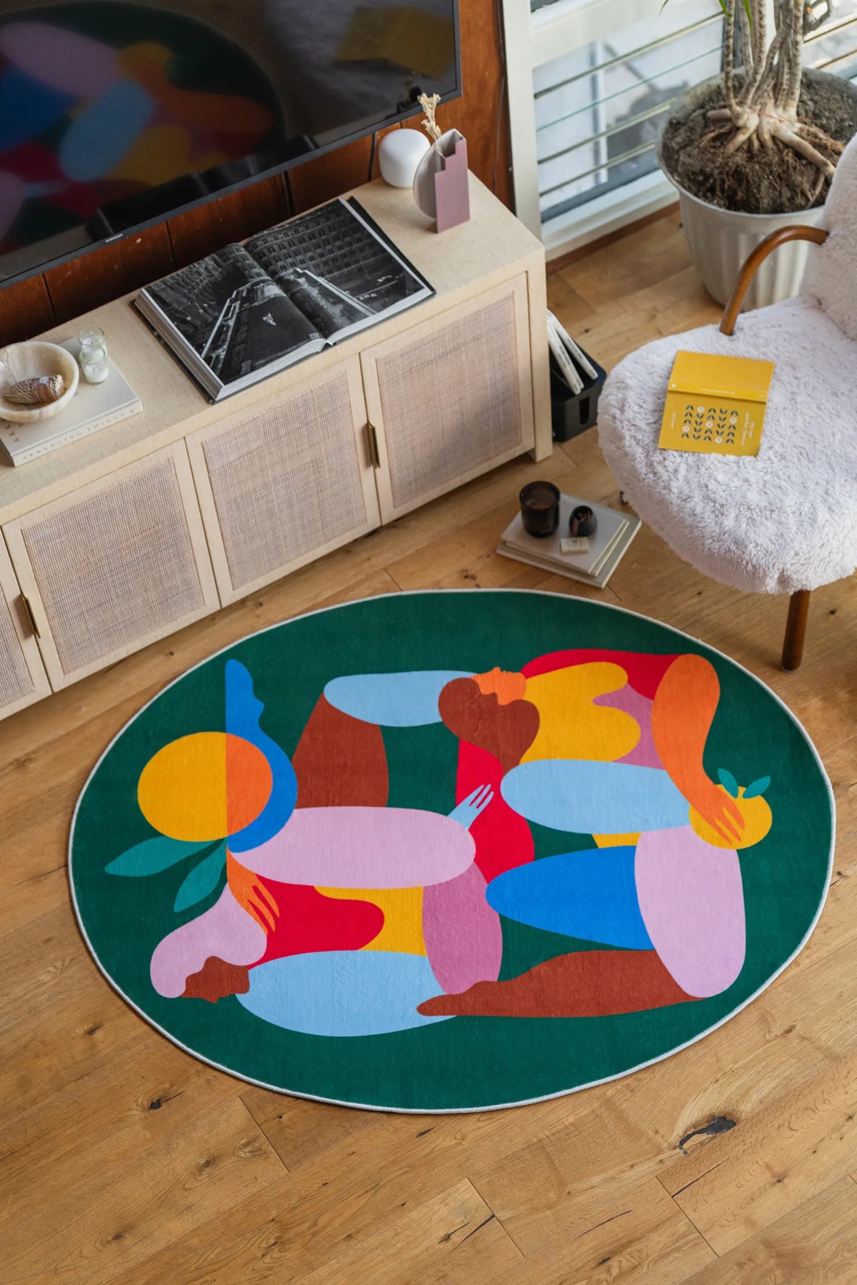 Fruitvine green rug shown under a cozy reading nook setup with boucle chair and low console cabinet