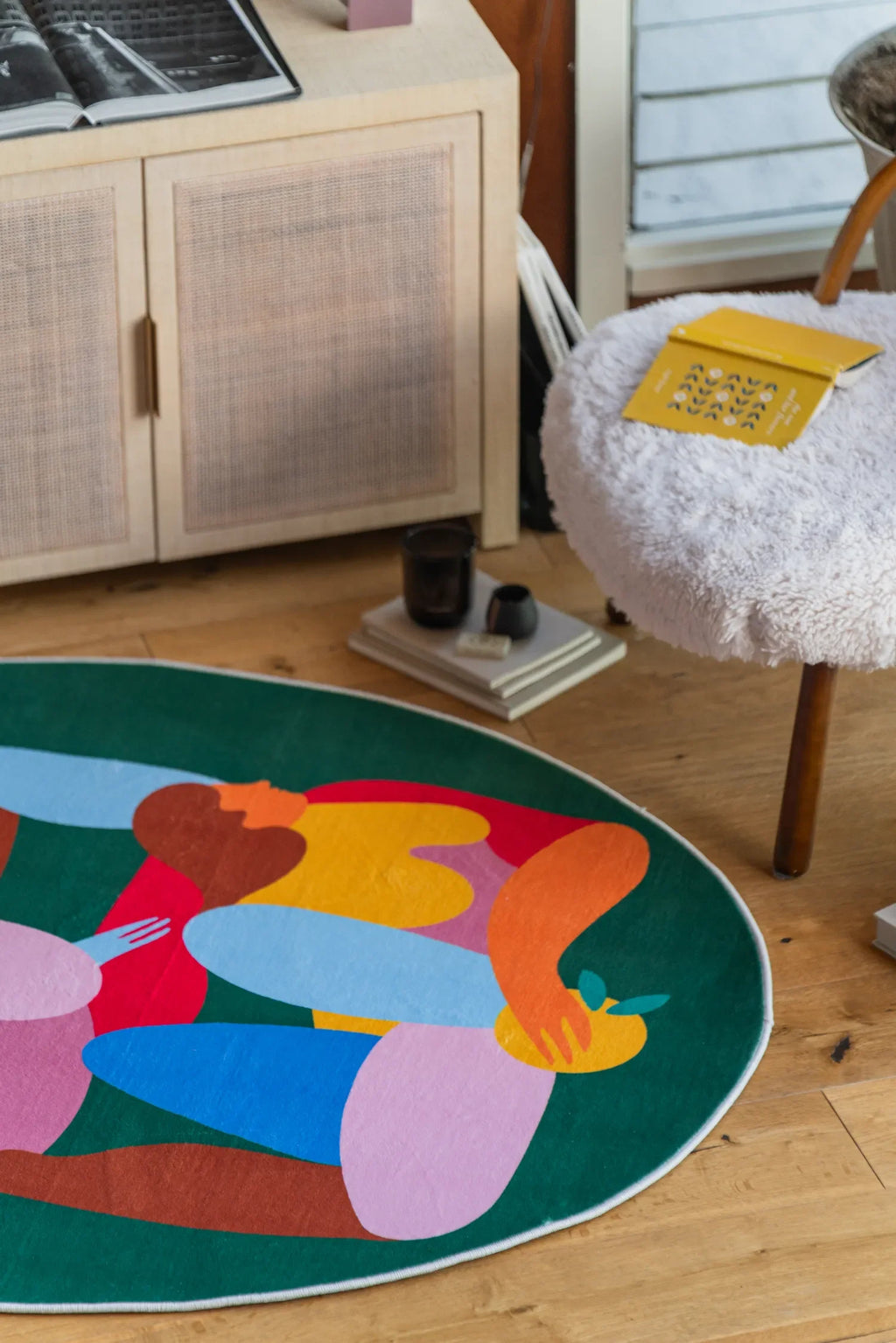 Fruitvine green rug partially visible beneath a boucle chair and cabinet in a relaxed reading corner.