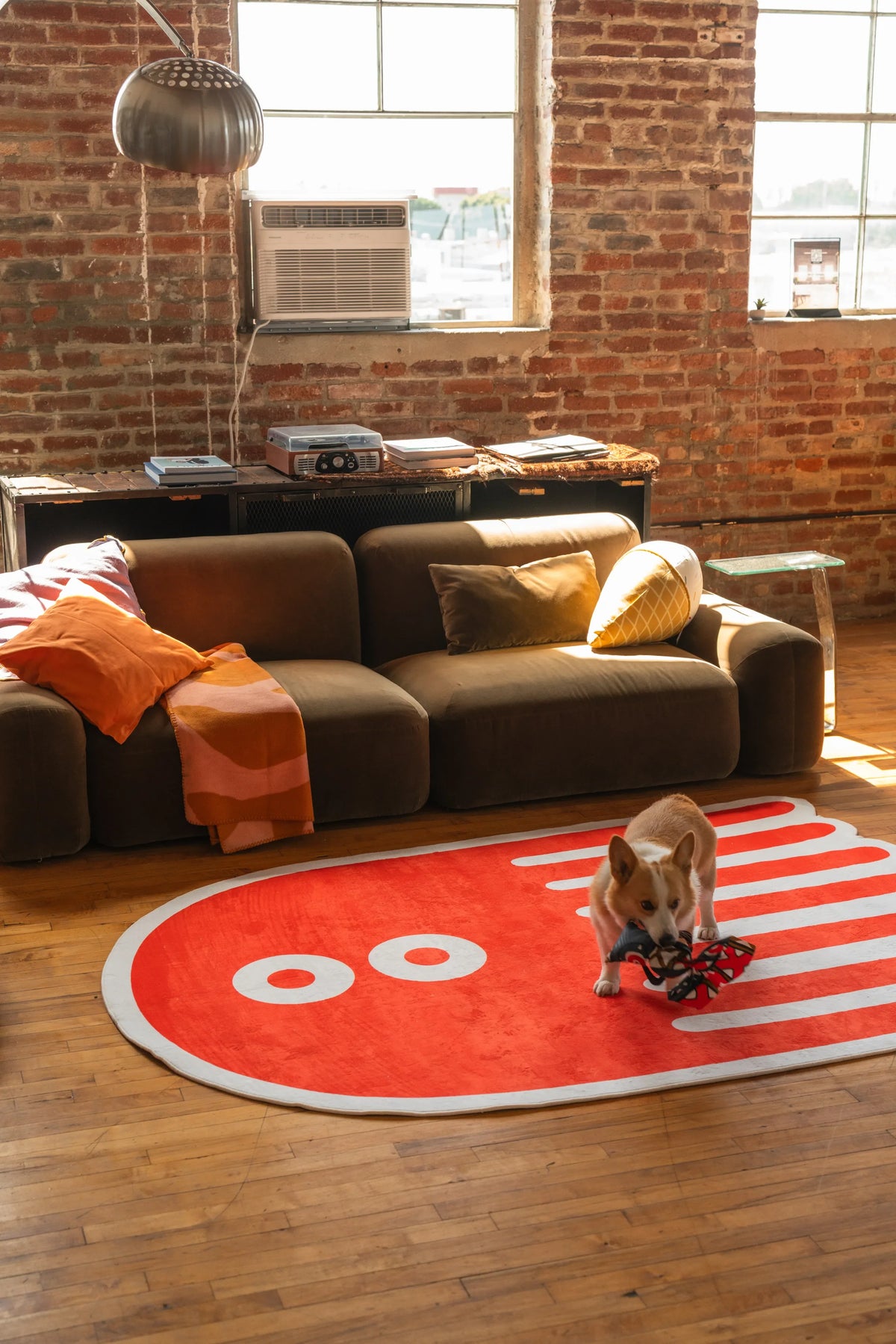 Orange abstract rug with white eyes and striped tentacle design on hardwood floor, modern aesthetic rug decor