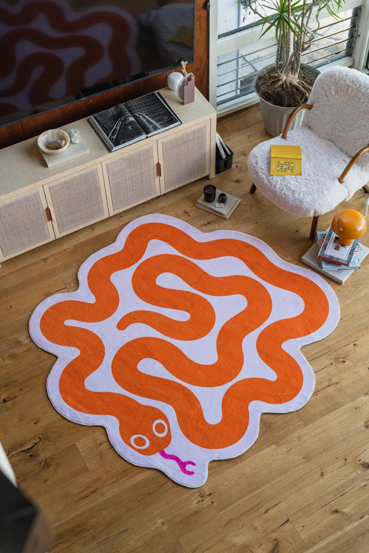 Detail of the snake’s head and tongue on the orange snake rug placed on warm wood flooring.