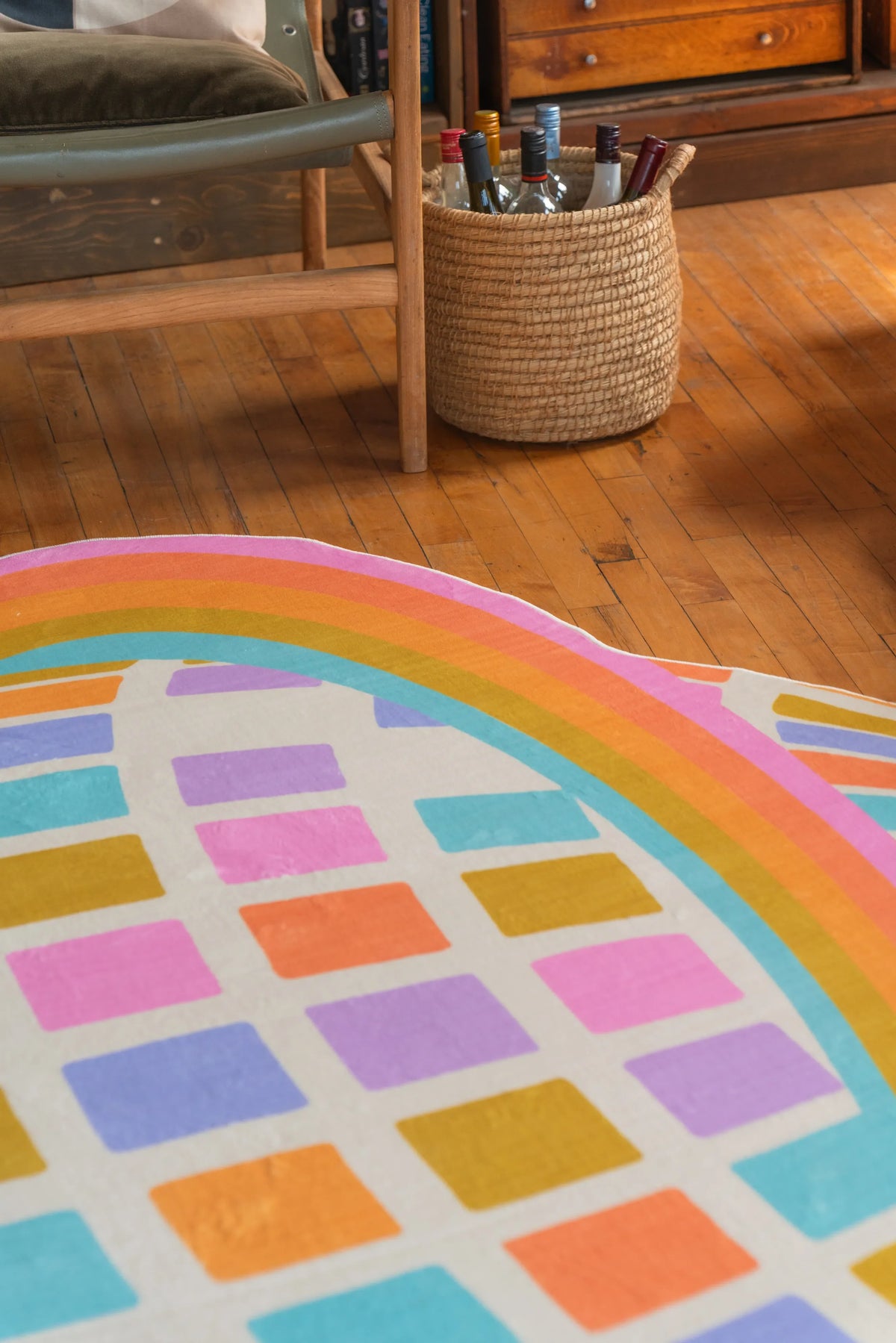 Colorful Disco Planet Checkered Rug by Darra Sargnt shown beside a chair and basket on wood floor