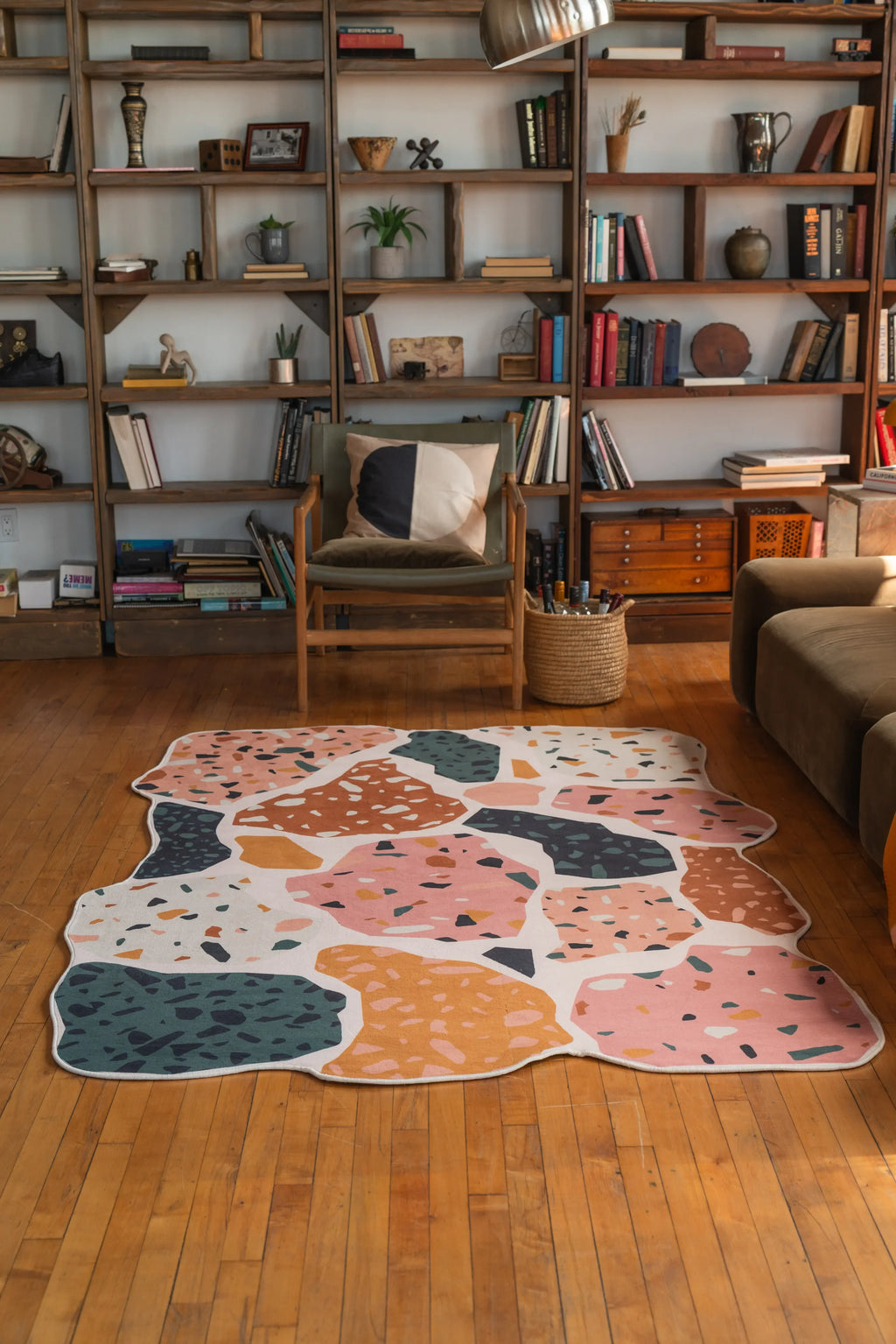 Multicolor terrazzo-style rug with organic edges placed in a bright reading nook with wood floor and mid-century furniture