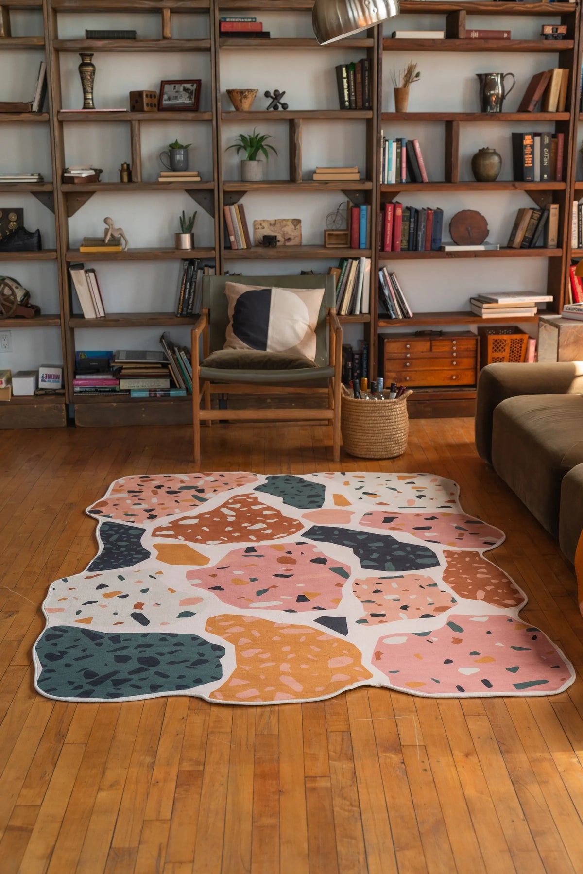 Multicolor terrazzo-style rug with organic edges placed in a bright reading nook with wood floor and mid-century furniture