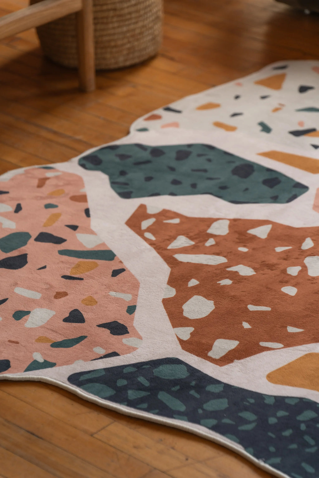 Detail of the multicolor Mosaic Flow Abstract Rug featuring organic shapes and speckled patterns on wooden floor