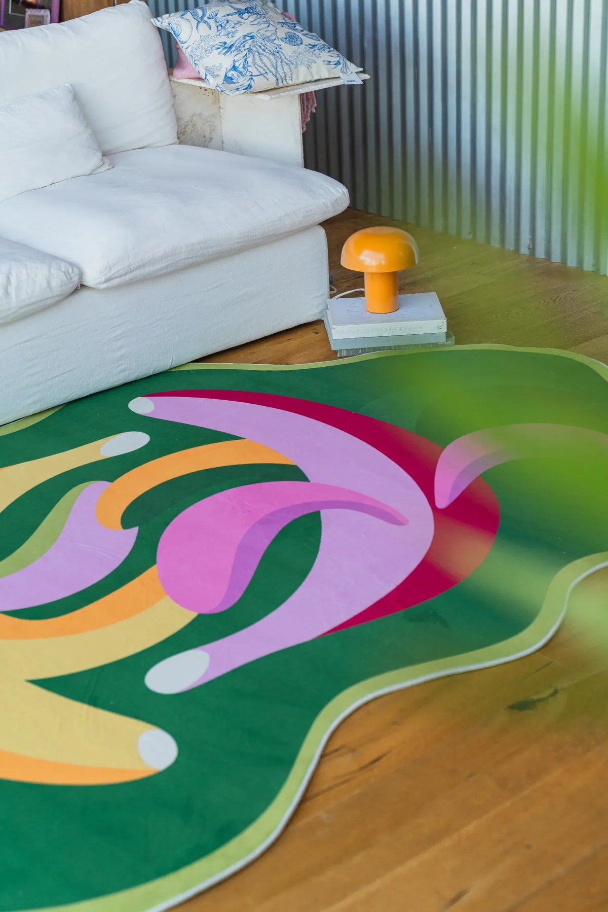 Close-up of the banana-shaped rug near a white sofa and small mushroom lamp.