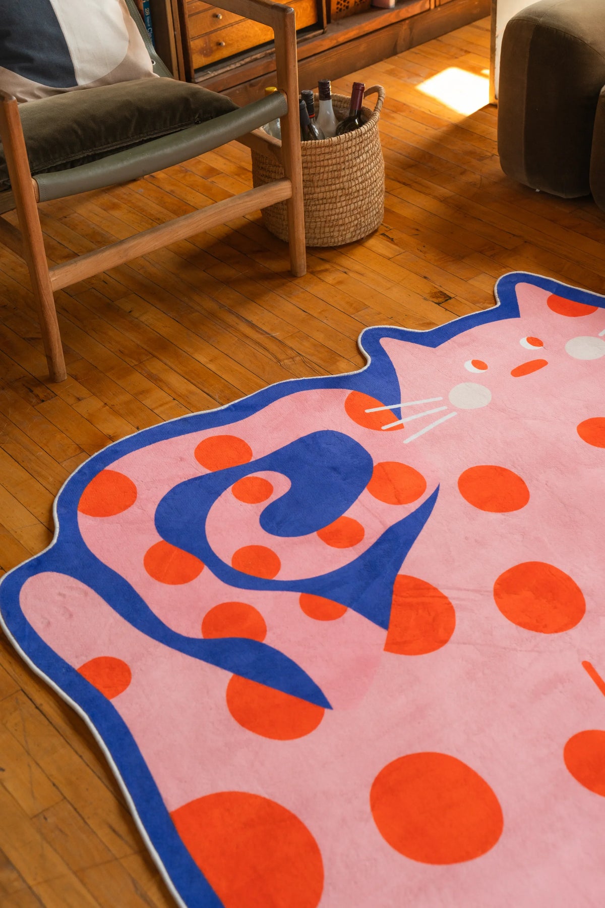 Playful navy blue rug with bold dots positioned near a wooden chair on warm wood floor