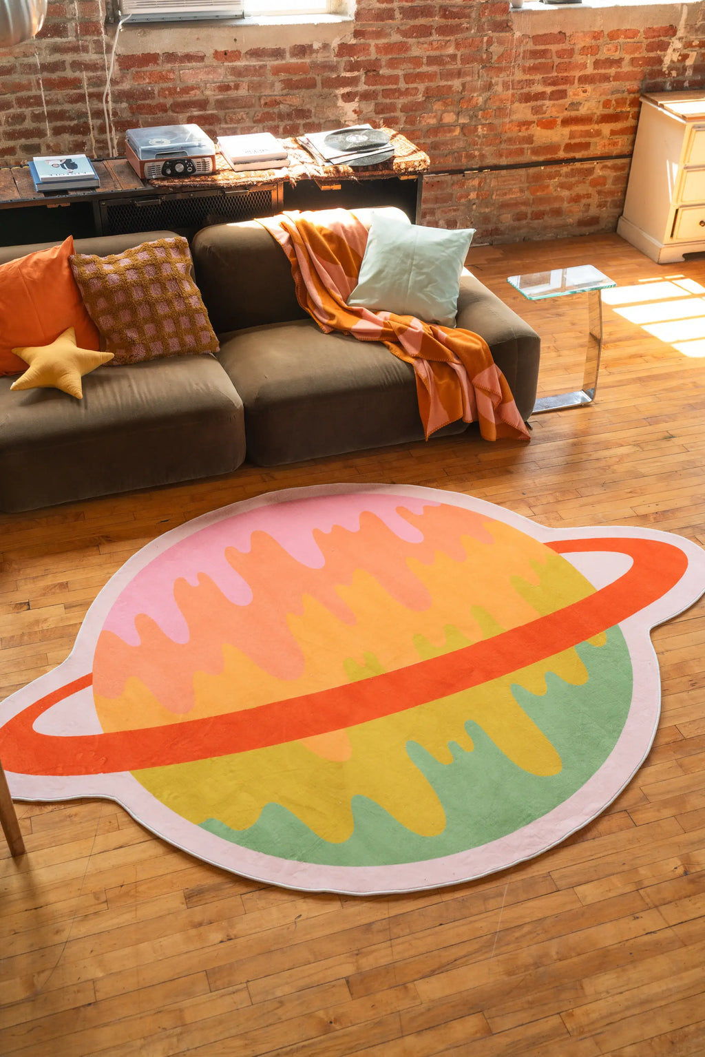 Colorful planet-shaped rug styled in a warm-toned living room with sofa and pillows