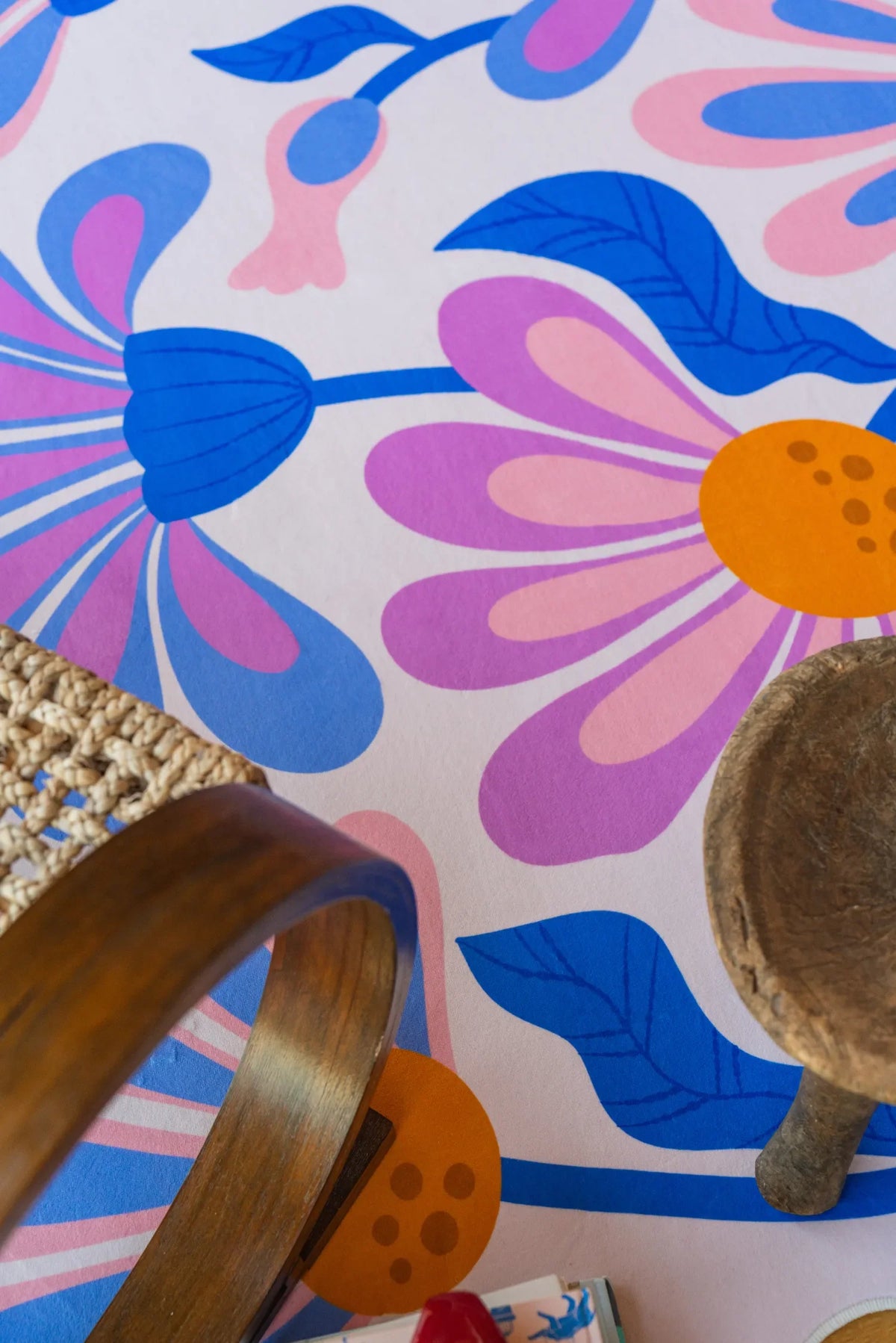 Close-up of lilac floral wavy rug under a curved chair leg on light wood flooring.