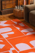 Orange Geometric Patchwork Rug with organic shapes styled beside a low modular seat, contemporary accent rug