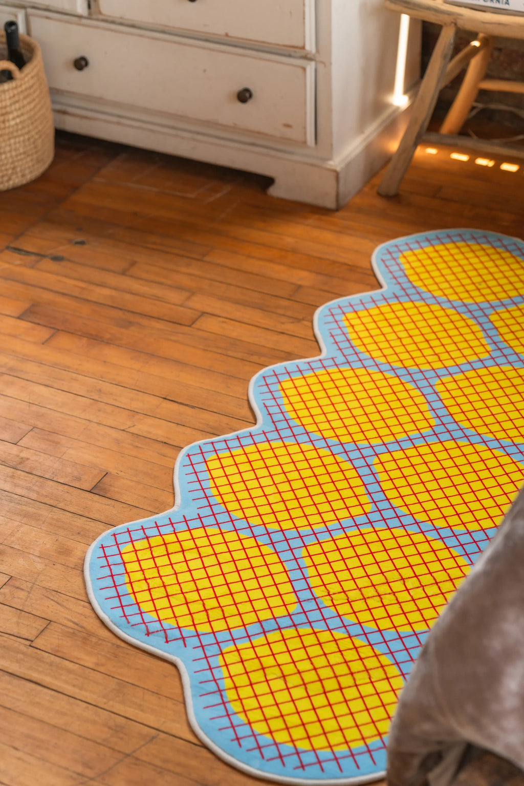 Yellow grid rug in curved lemon shape laid out across honey-toned wood floor
