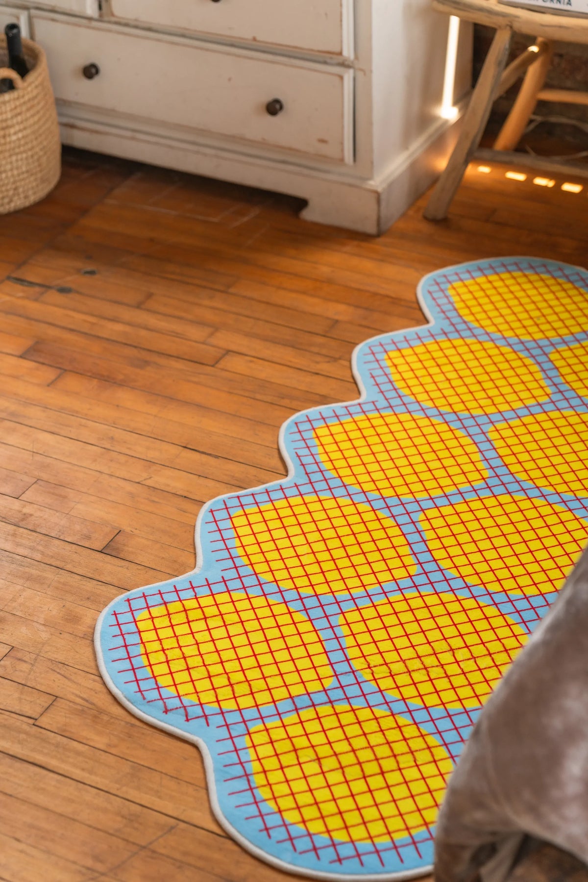 Yellow grid rug in curved lemon shape laid out across honey-toned wood floor