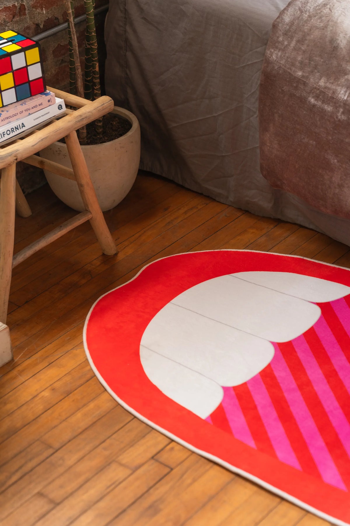 Red and white pop art area rug with mouth detail near bed and bedside stool in bedroom