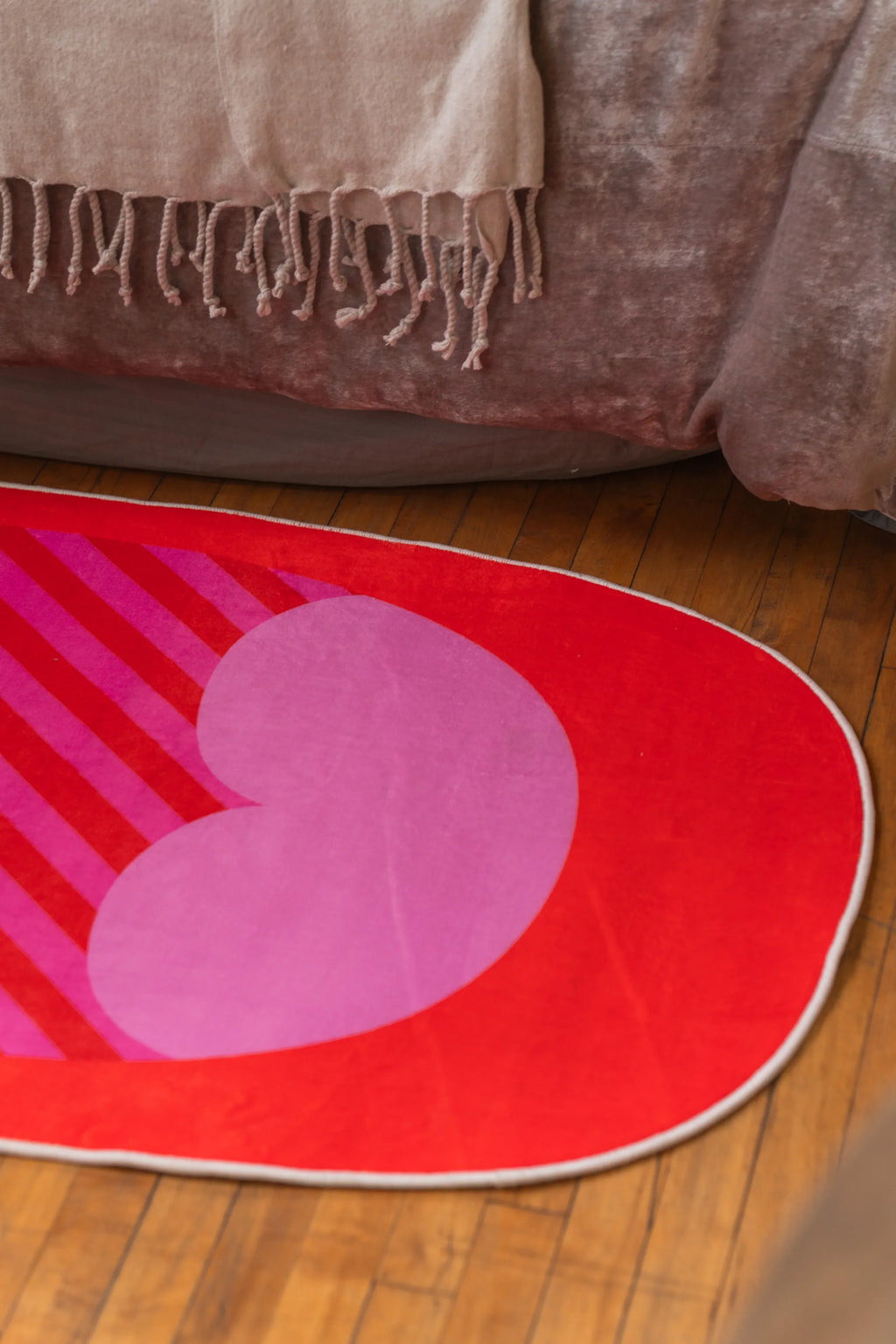 Heart-shaped section of red pop art bedroom rug with bold pink and red stripes near bed