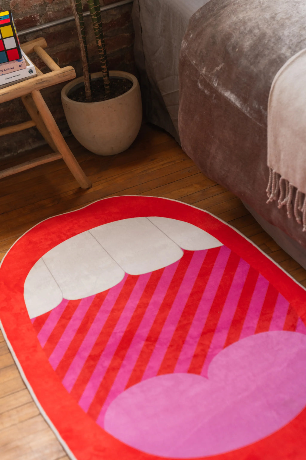 Bold Red Mouth Pop Art area rug with pink heart and teeth detail beside bed on wood floor