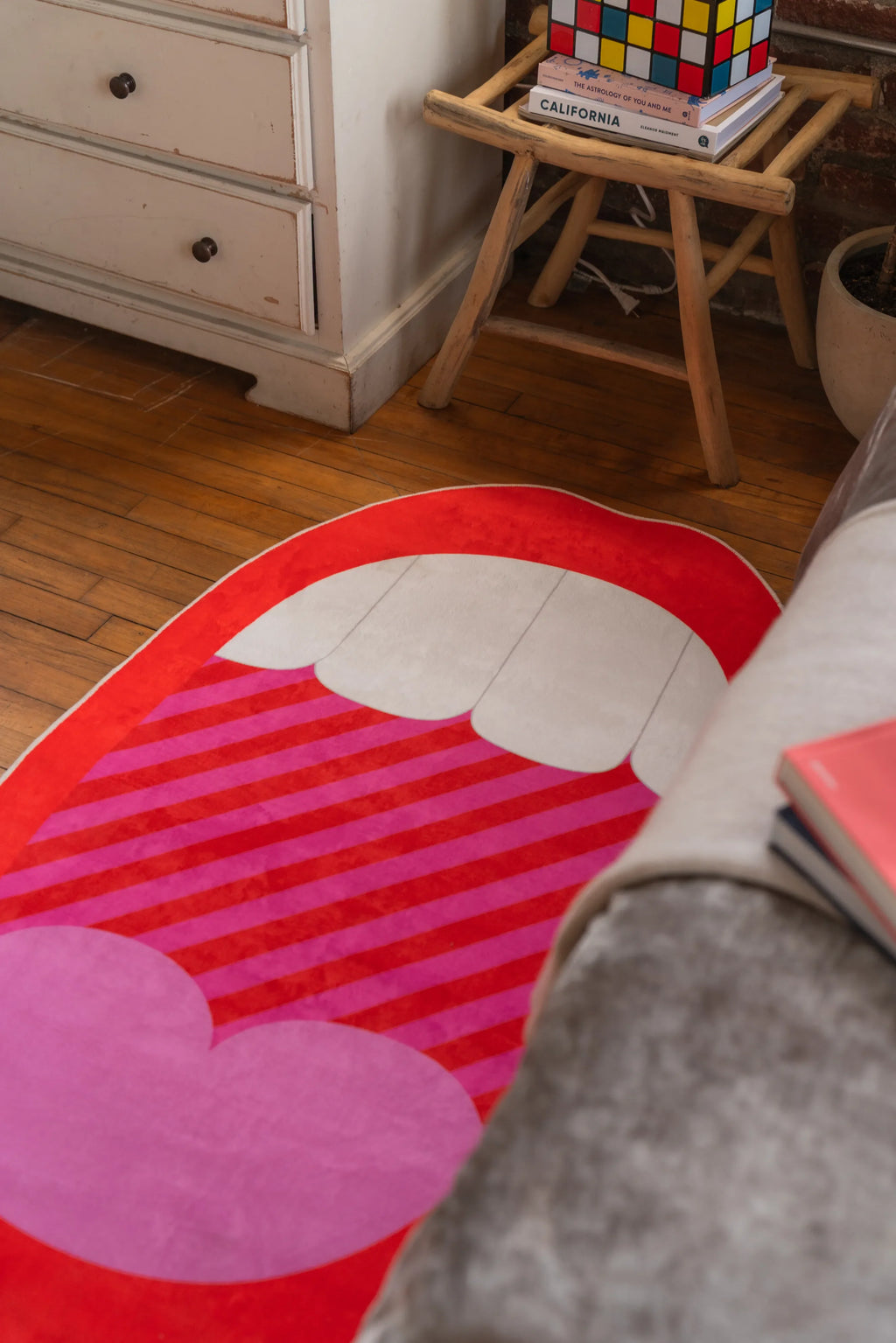 Graphic pop art bedroom rug with red lips and pink heart shape near white dresser and stool