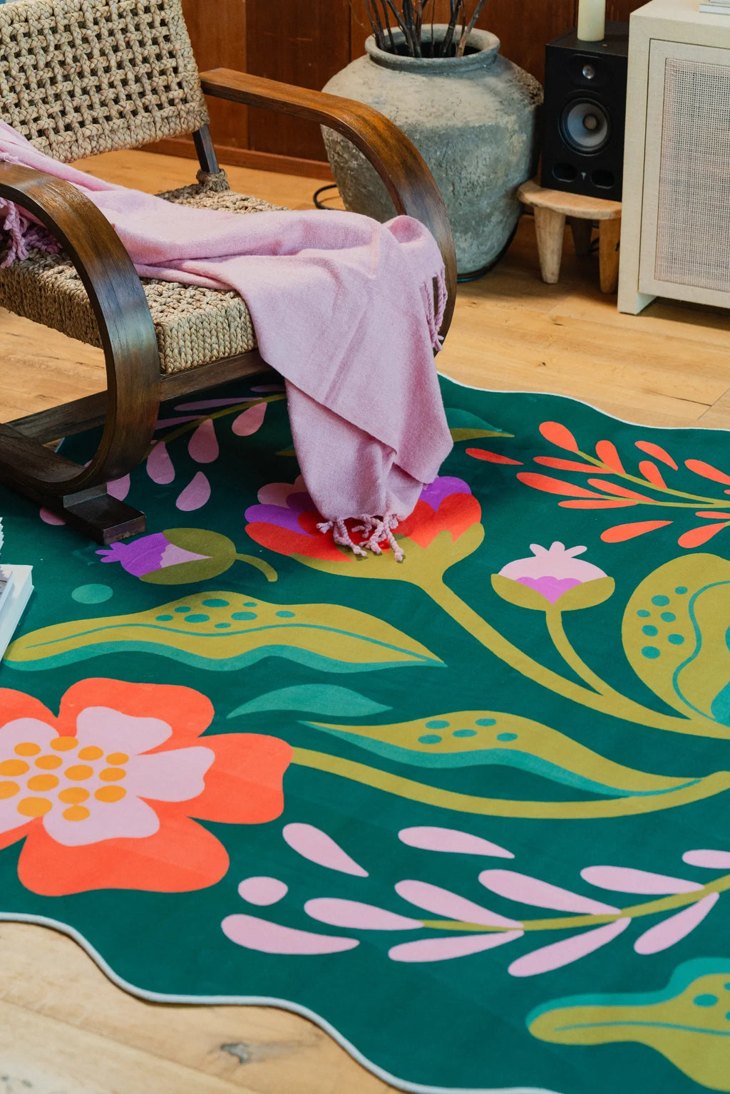 Close view of the floral wavy rug with bold orange and purple accents beside a wooden chair on wood floor.