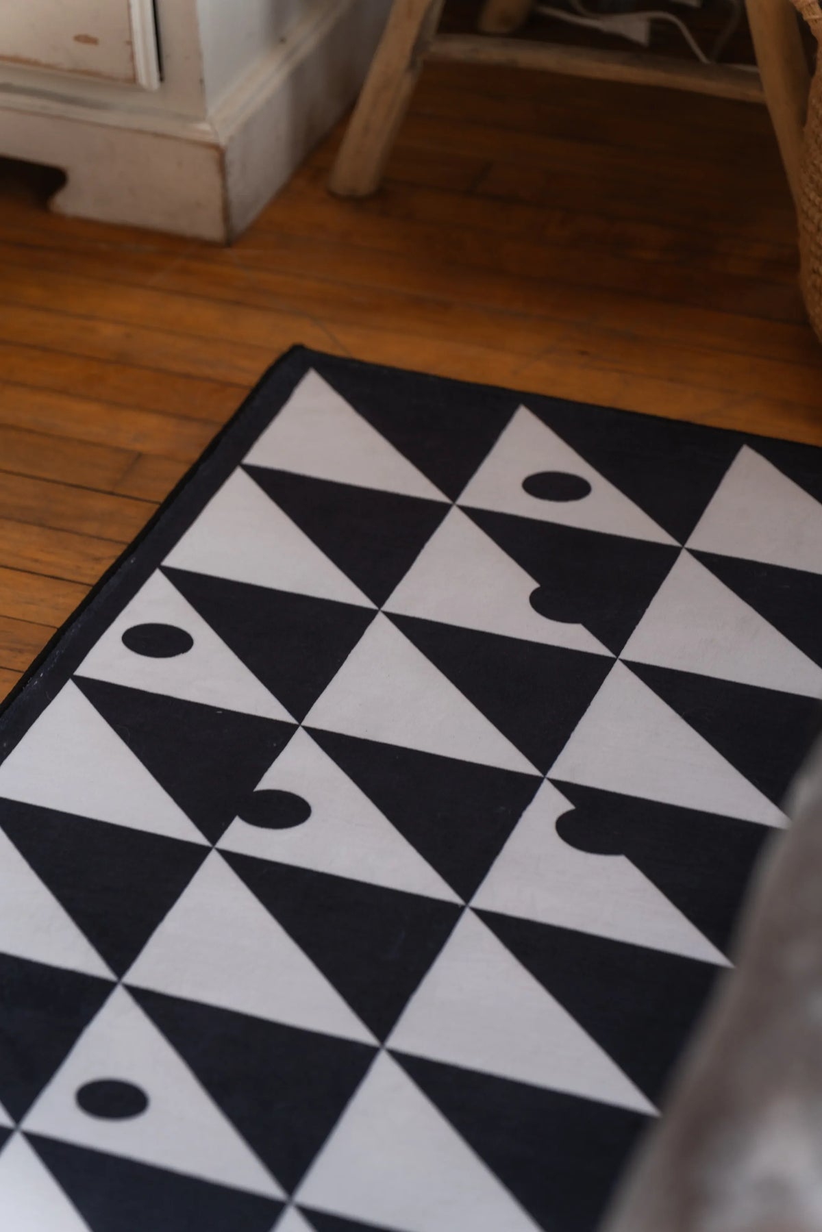 Close-up of black and white runner rug with geometric triangles and circle details on a hardwood floor.