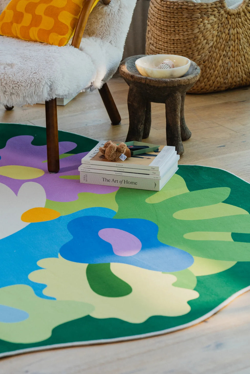 Close-up of colorful floral rug beside a woven basket and stool in the living room near the window.