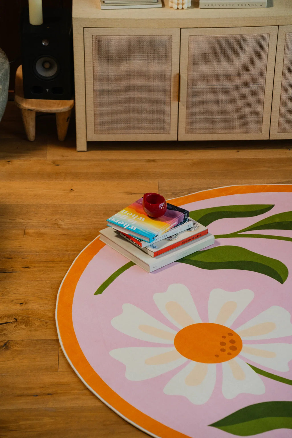 A closer view of the pink daisy-patterned rug beside a white chair with a pink throw