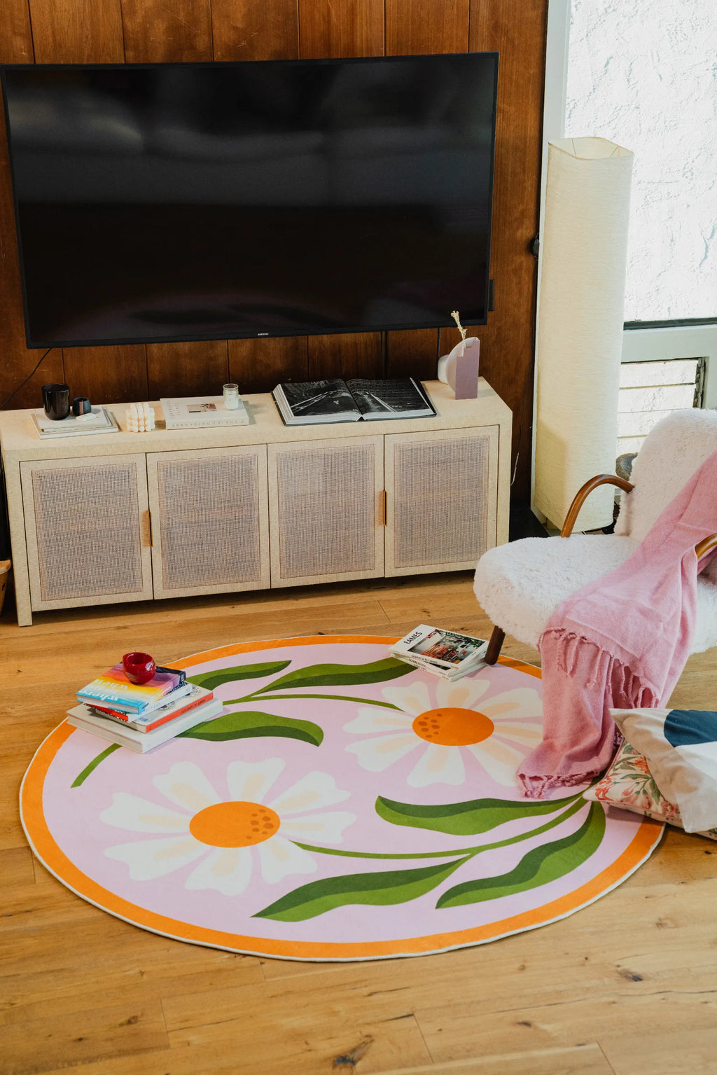 Dual daisy rug centered in a casual corner with boucle chair and low cabinet on pale wood floor.