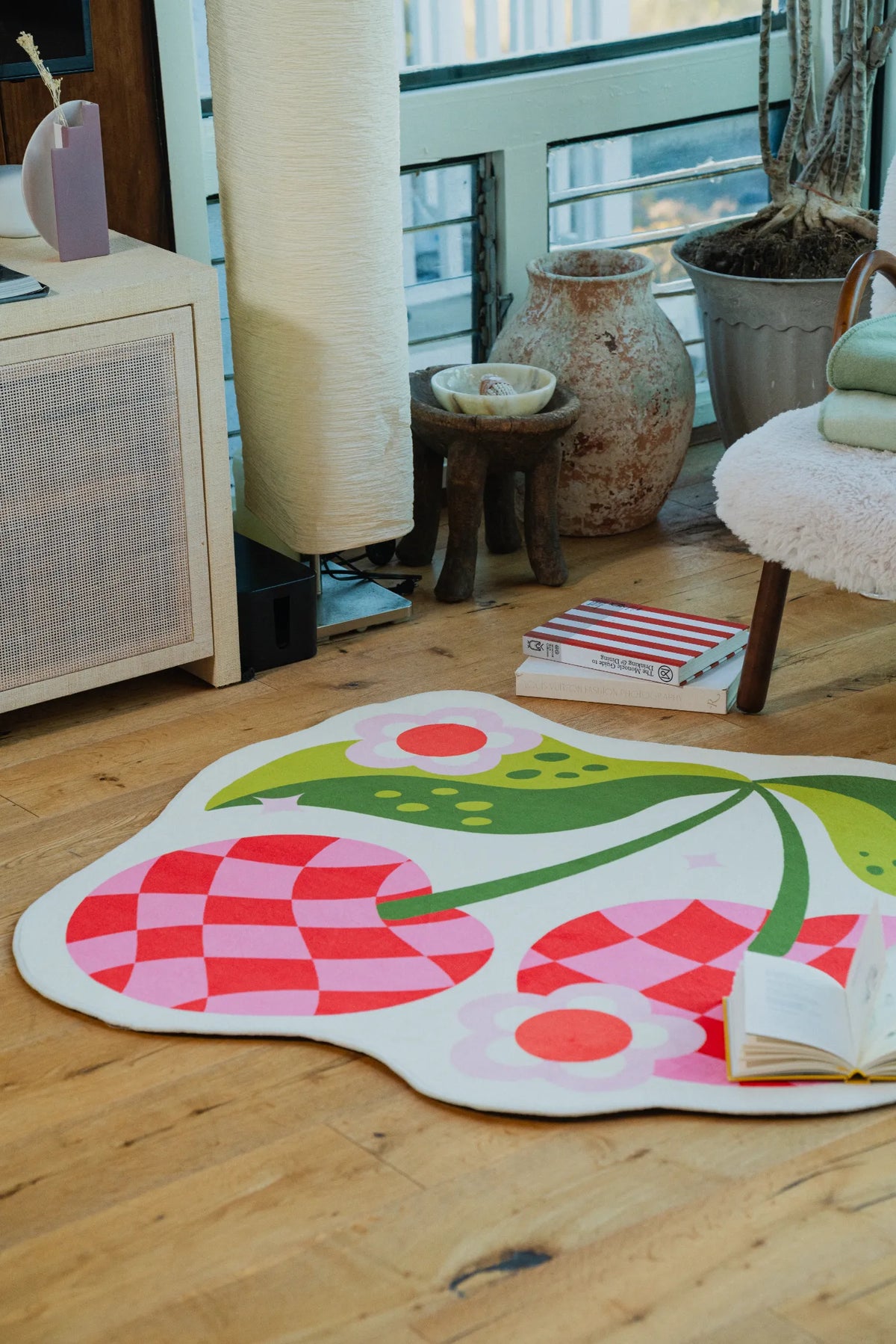 Checkered cherry rug placed in a bright corner beside a boucle chair on natural wood floor.