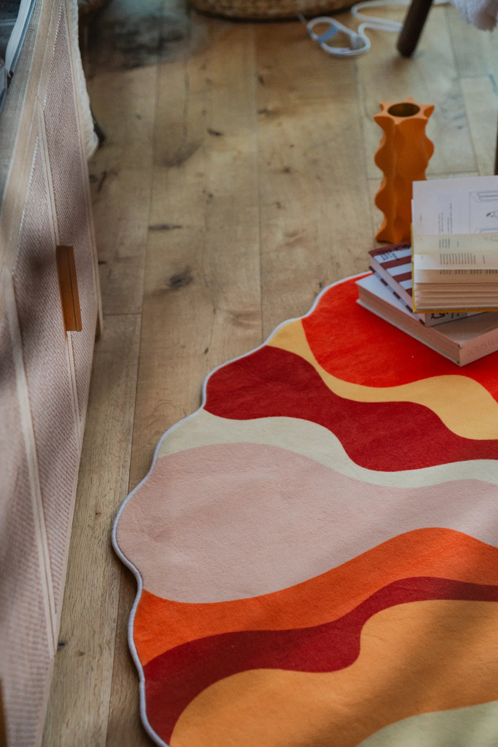 Detail of the wavy sunbeam pattern on the rug, showing vibrant red and orange tones under soft lighting.
