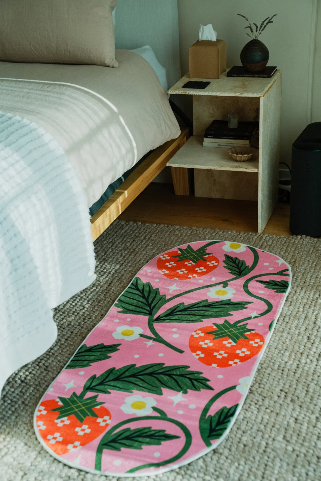 The Sicilian Strawberry Pink Runner Rug by Megan Roy is laid beside a bed on textured carpet floor.