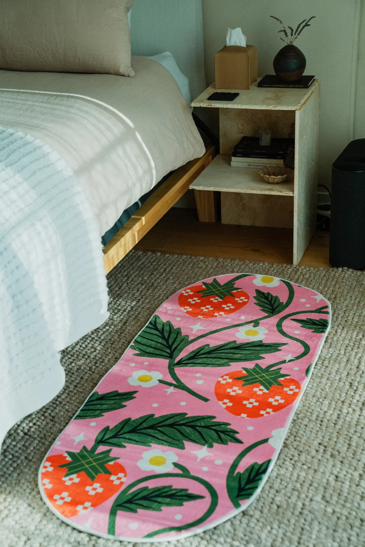 The Sicilian Strawberry Pink Runner Rug by Megan Roy is laid beside a bed on textured carpet floor.