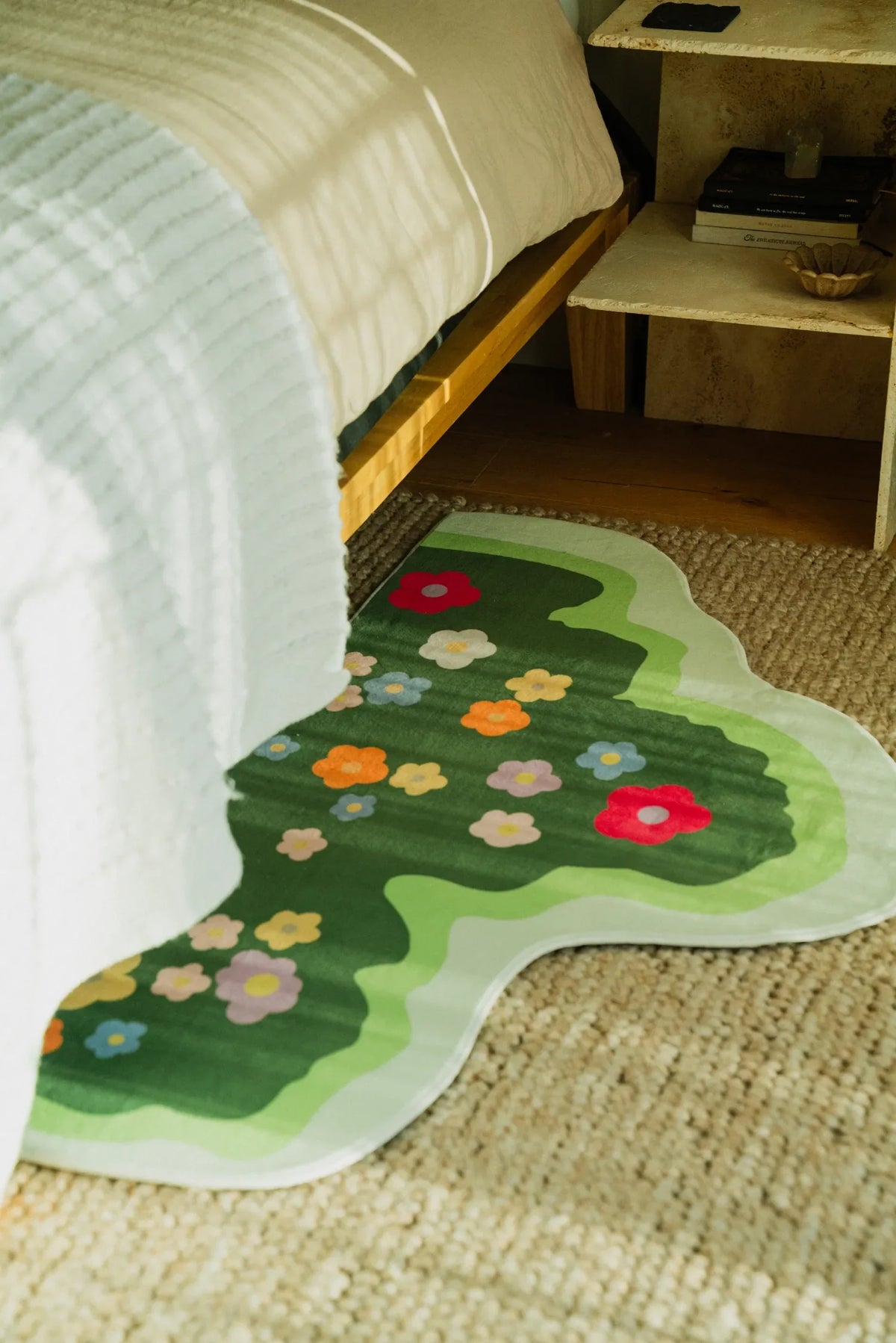 Floral irregular runner placed next to a wooden bed in a sunlit bedroom with a woven rug underneath.