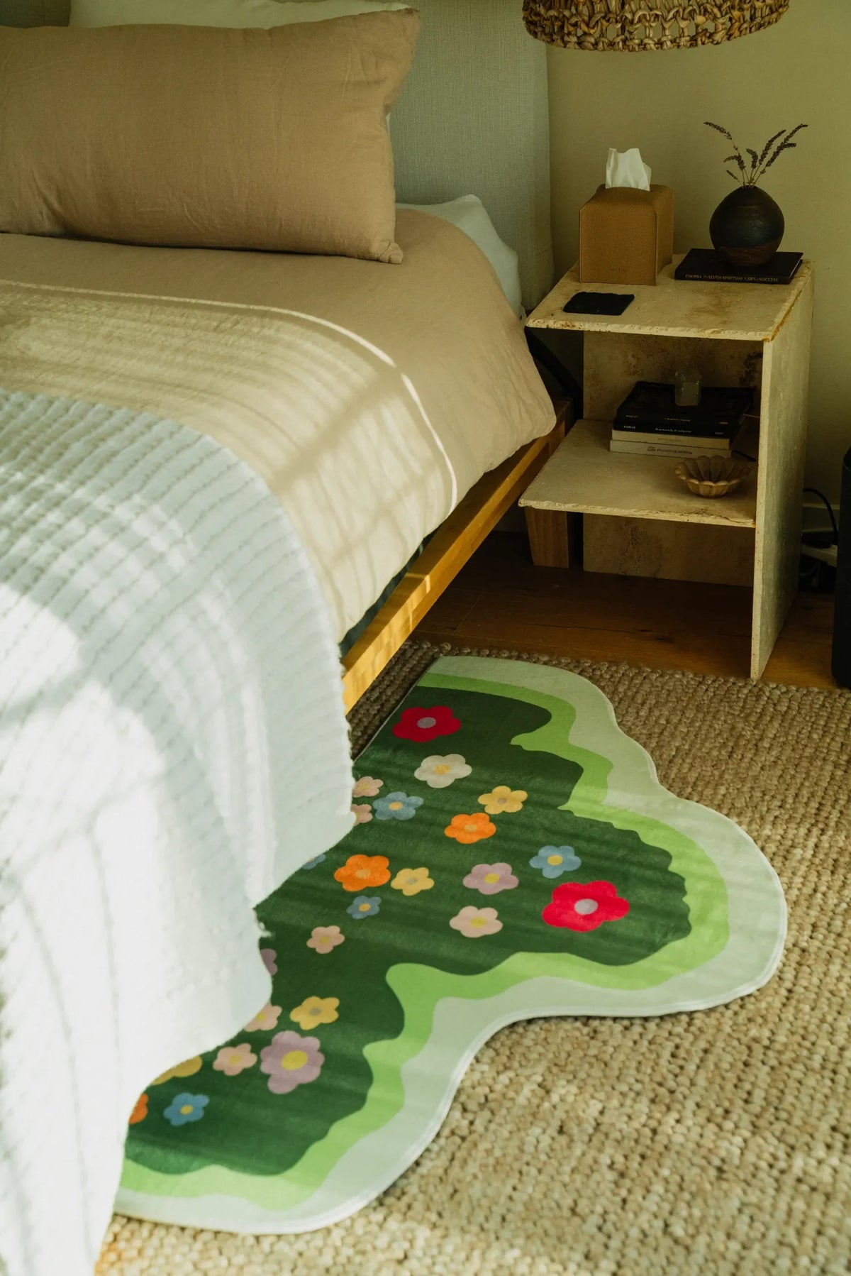 Another view of the floral runner tucked partially under a bed, complementing neutral bedding and a travertine nightstand.