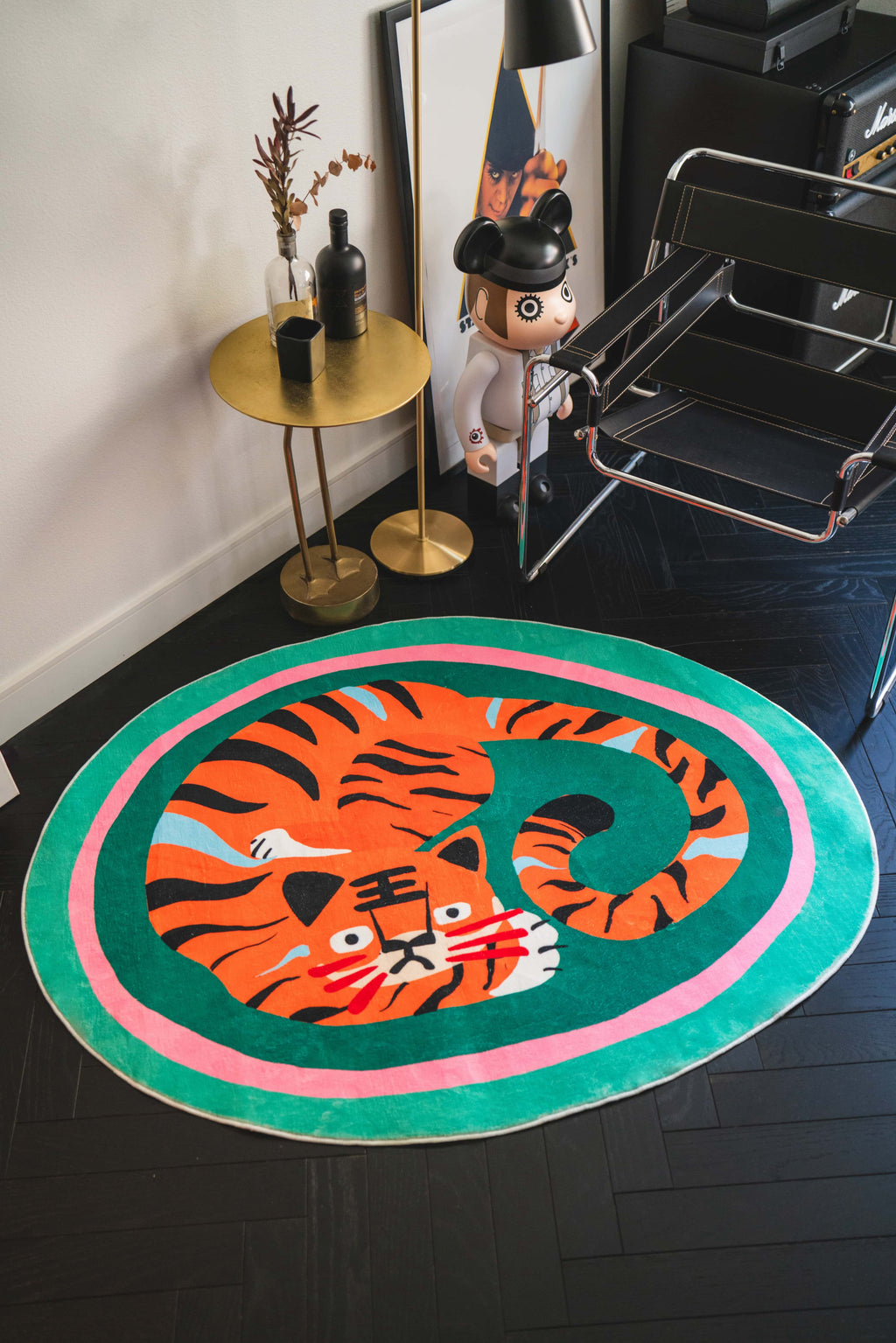 Oval Tiger Area Rug by Lu Yang adds bold personality to a modern corner, styled with gold accents and a black leather chair.