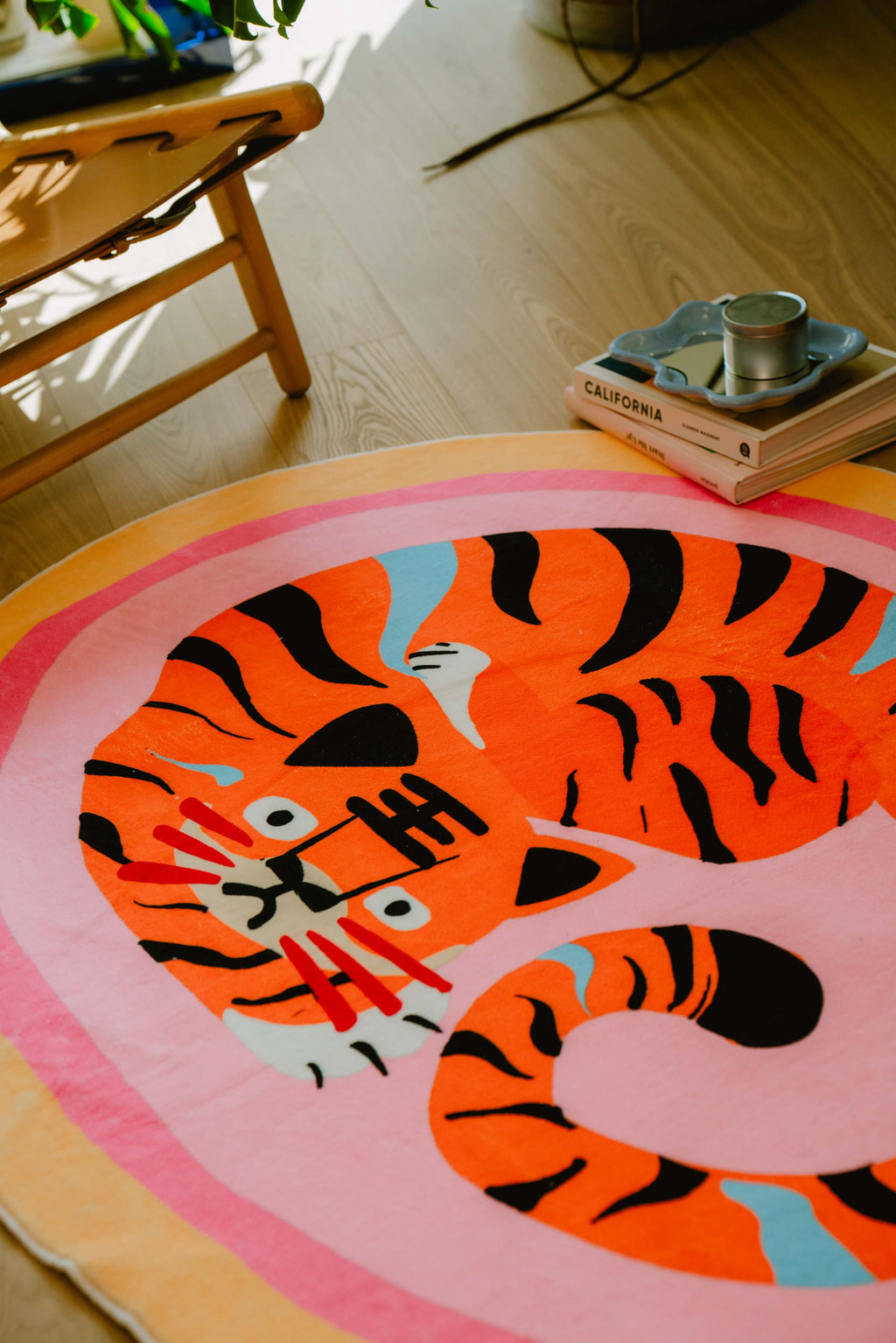 Sunlit corner with pink tiger rug partially under a chair, warm tones highlight the vibrant pattern and playful design.