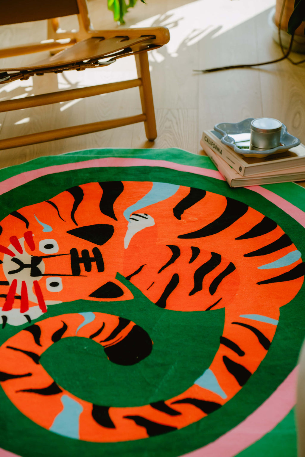 Bright morning light illuminates the tiger rug’s expressive face and curled tail, paired with wooden furniture and curated decor for a warm corner scene.